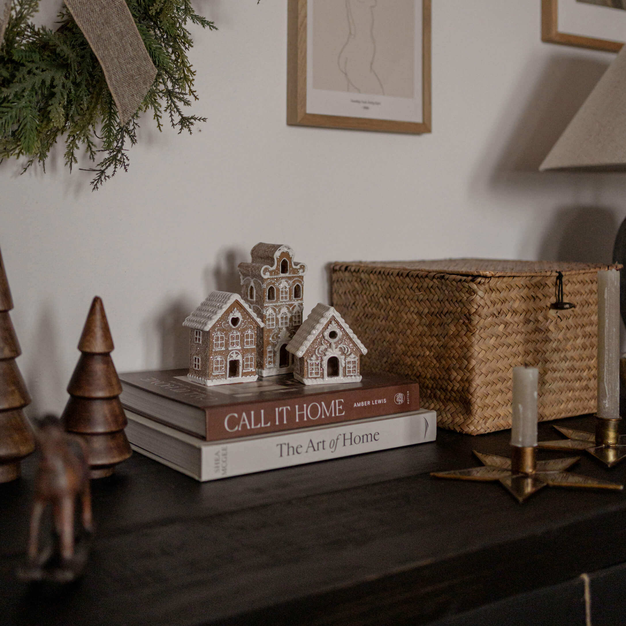 Casitas decorativas de arcilla sobre libros en mesa oscura con velas y elementos naturales