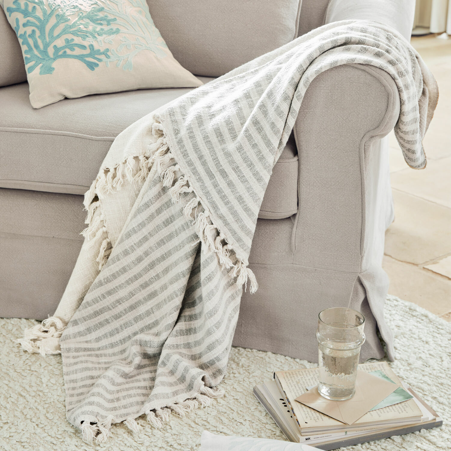Plaid Marpent Manta beige a rayas con flecos sobre sofá gris claro, accesorio acogedor para salón