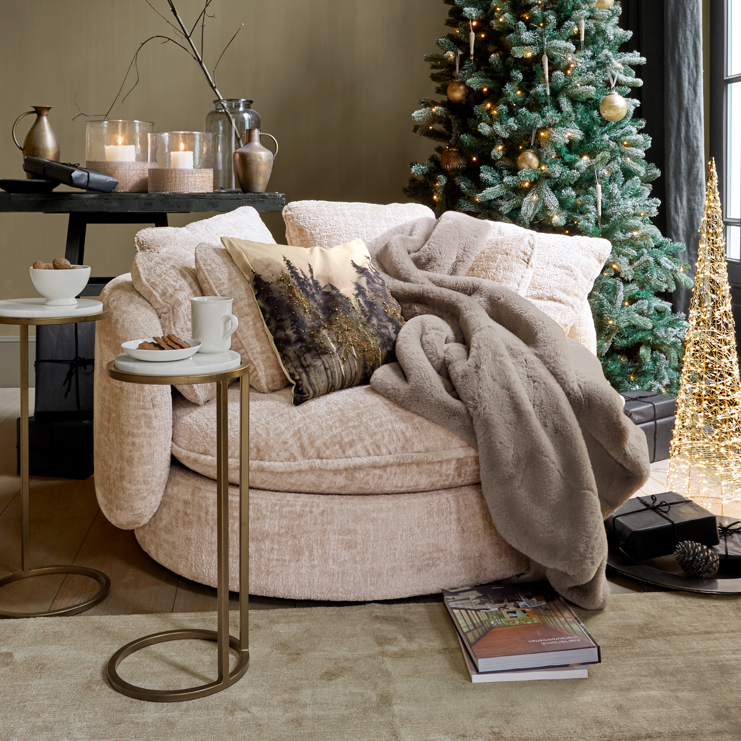 Sillón redondo beige con manta suave y cojín decorativo junto a árbol de Navidad y mesas auxiliares