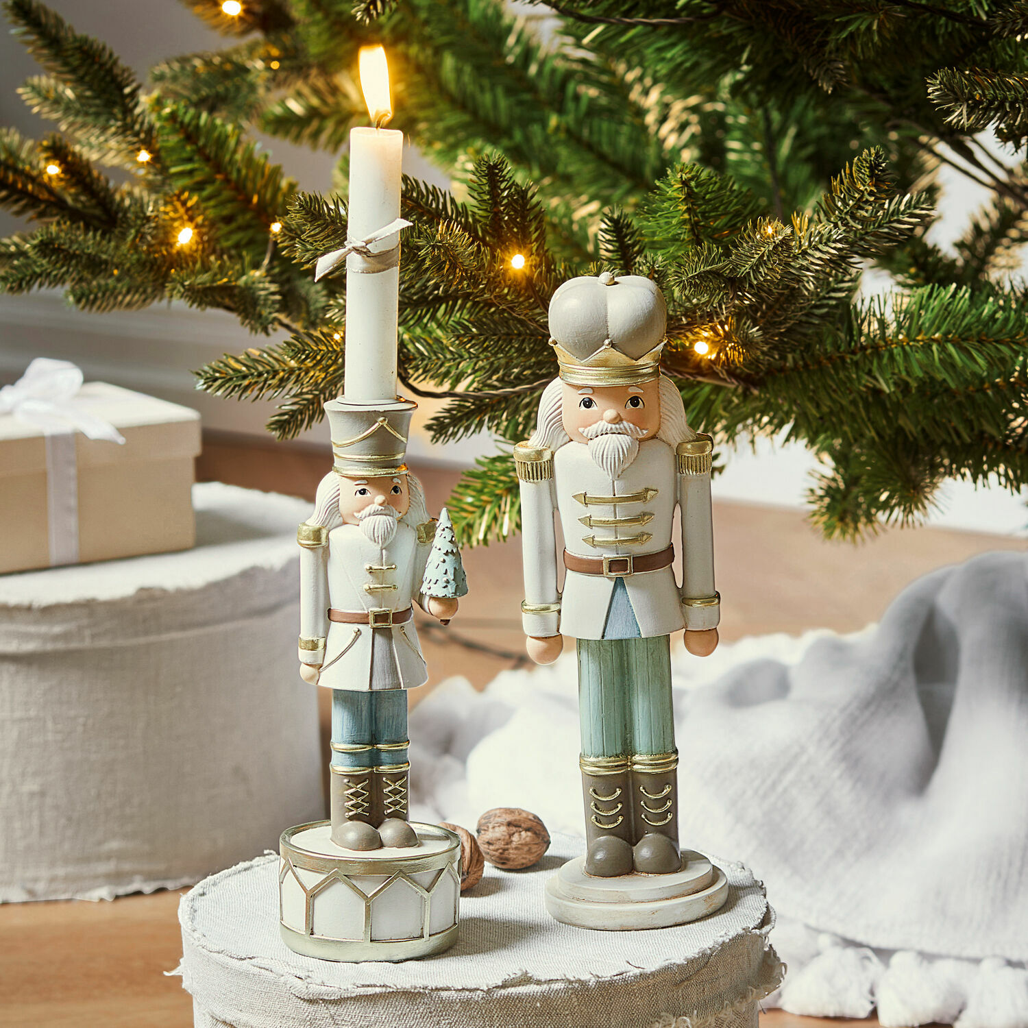 Set de 2 cascanueces decorativos con candelero Ellicott Figuras de cascanueces de madera en blanco y verde frente a un fondo navideño con ramas de pino iluminadas