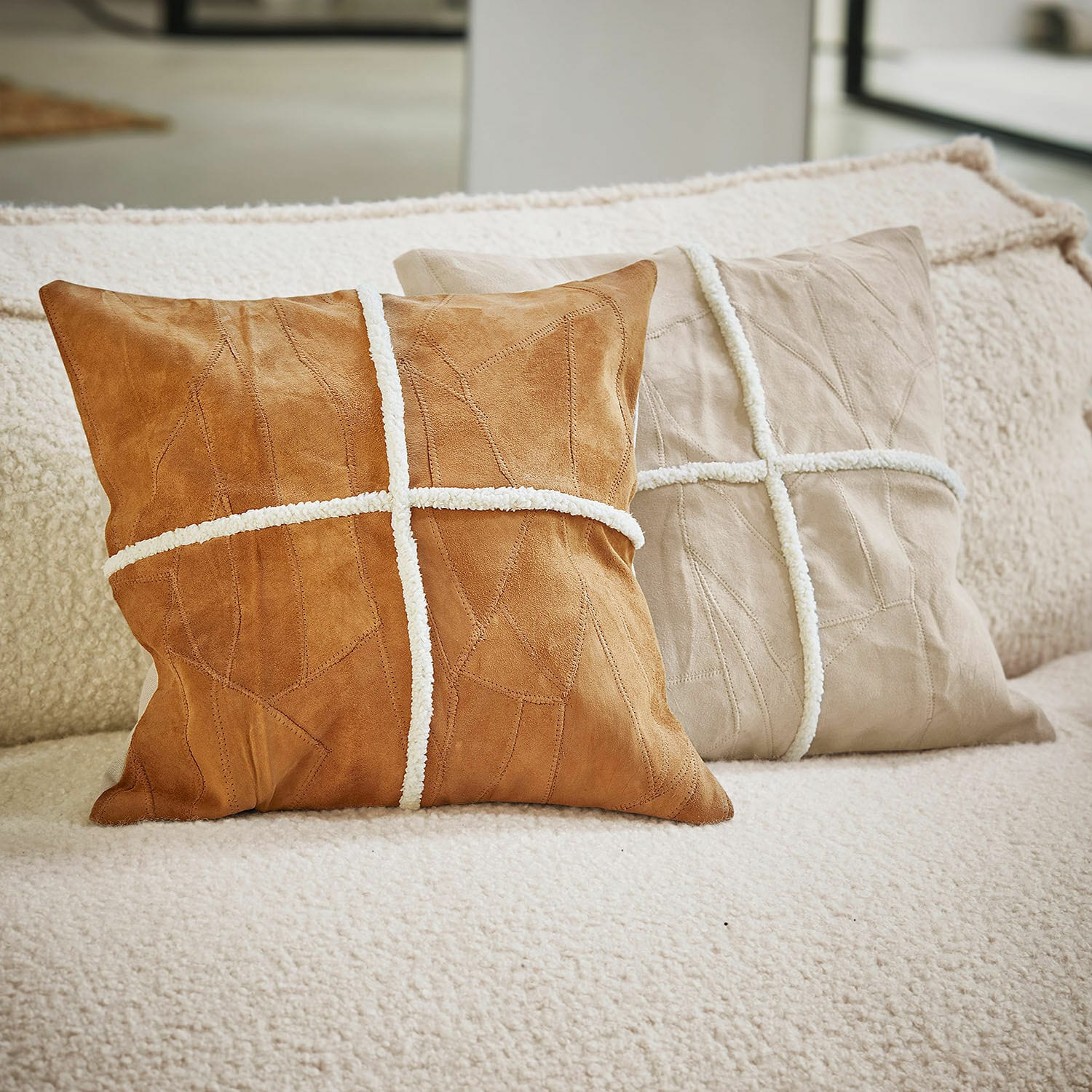 Set de 2 fundas de cojín Raminya Dos cojines decorativos de ante marrón y beige con tiras blancas sobre un sofá cómodo