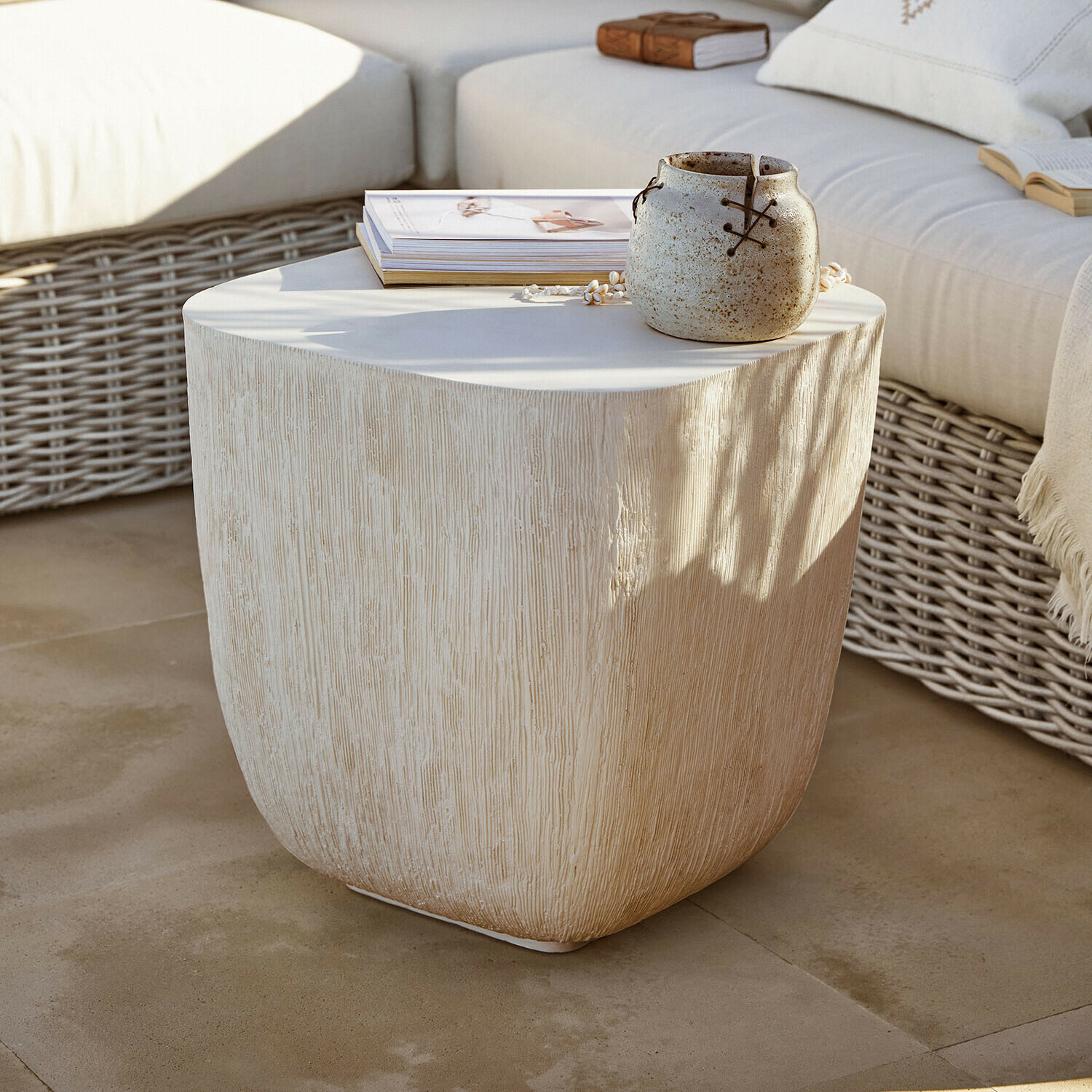 Mesa auxiliar Nélomiane Mesa auxiliar beige con textura de madera, cerámica y libros en terraza con sofá de mimbre