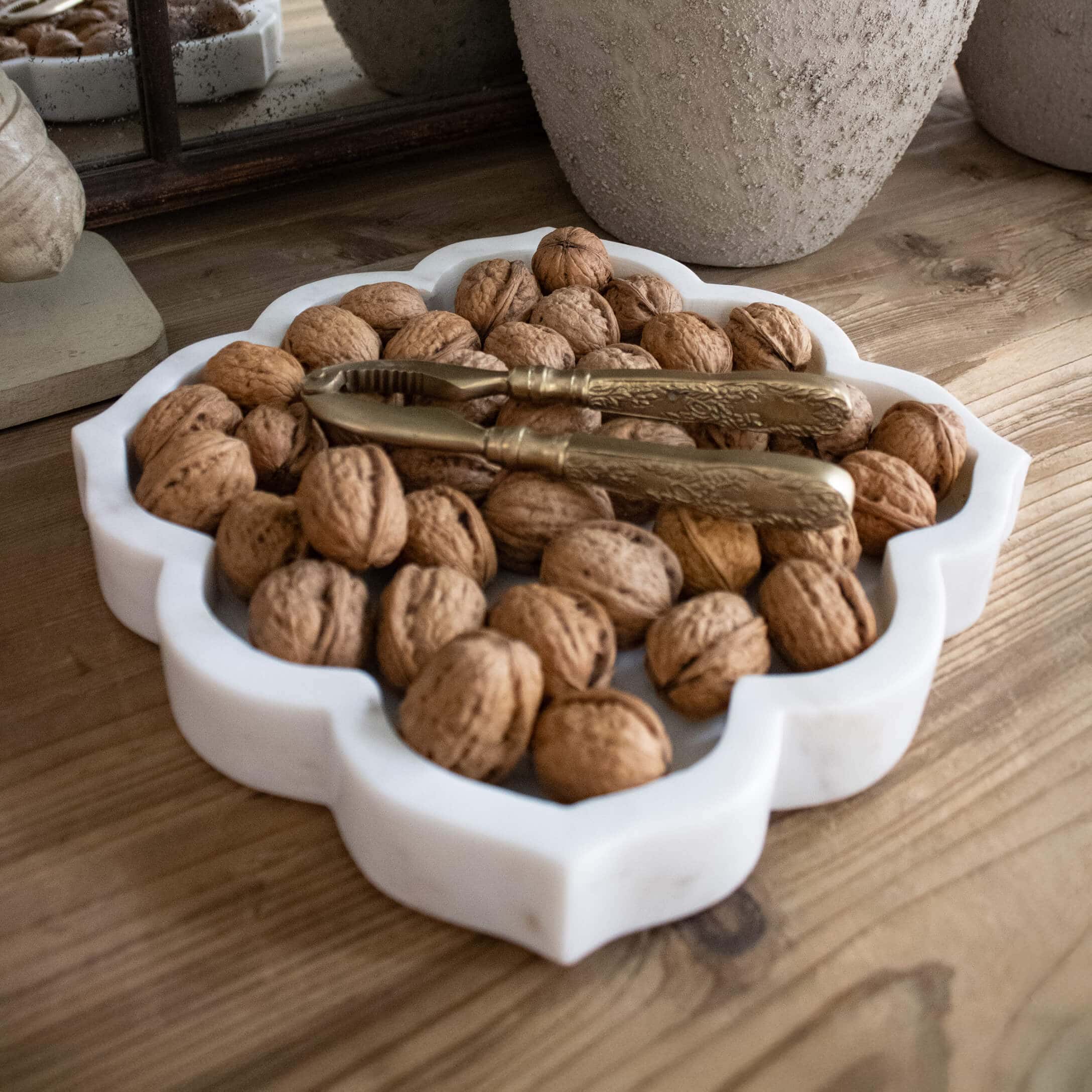 Bandeja de mármol blanco con nueces y cascanueces dorado sobre mesa de madera