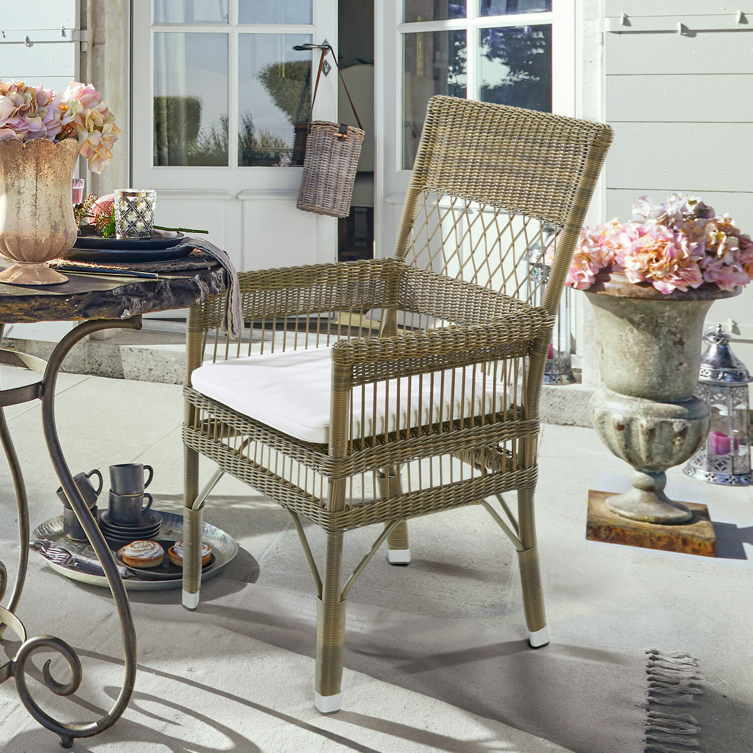 Silla de ratán natural con cojín blanco, ideal para jardín o terraza exterior