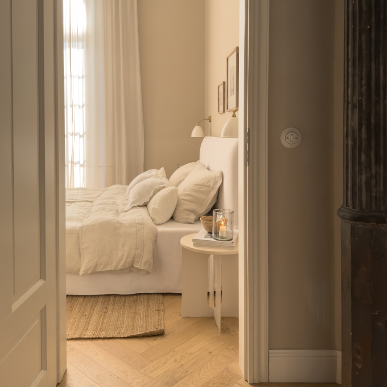 Dormitorio acogedor en tonos beige claros con cama y alfombra natural sobre suelo de madera clara