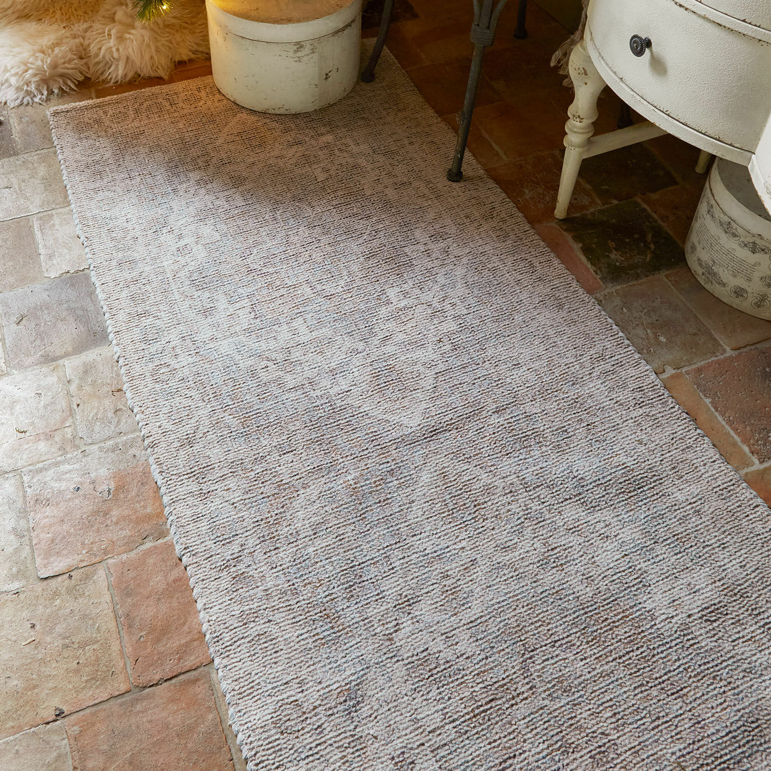 Alfombra beige con patrón sutil sobre suelo rústico, decoración de interiores y textil para el hogar