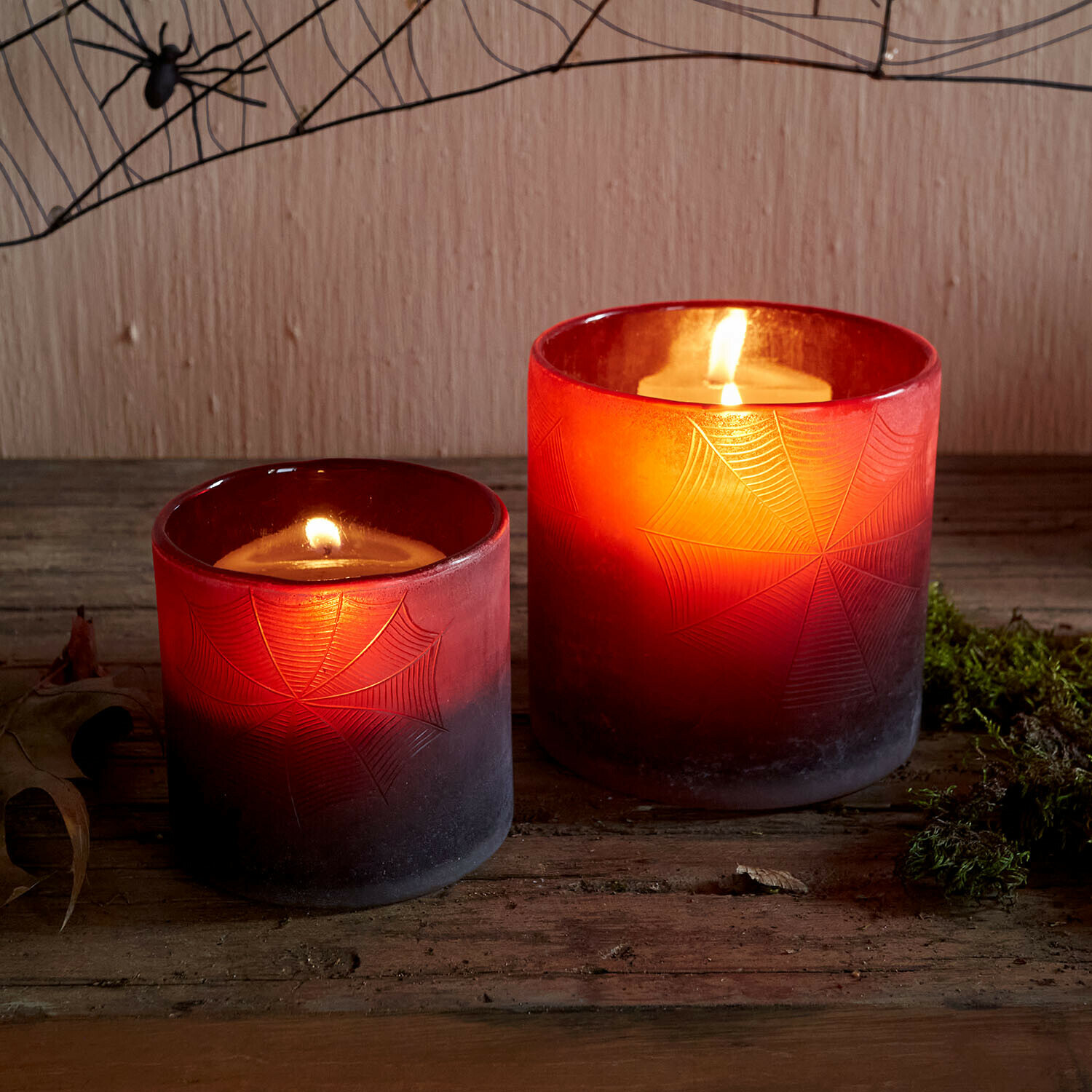 Portavelas Brannora Dos portavelas de vidrio rojo con diseño de telaraña, velas encendidas sobre mesa de madera