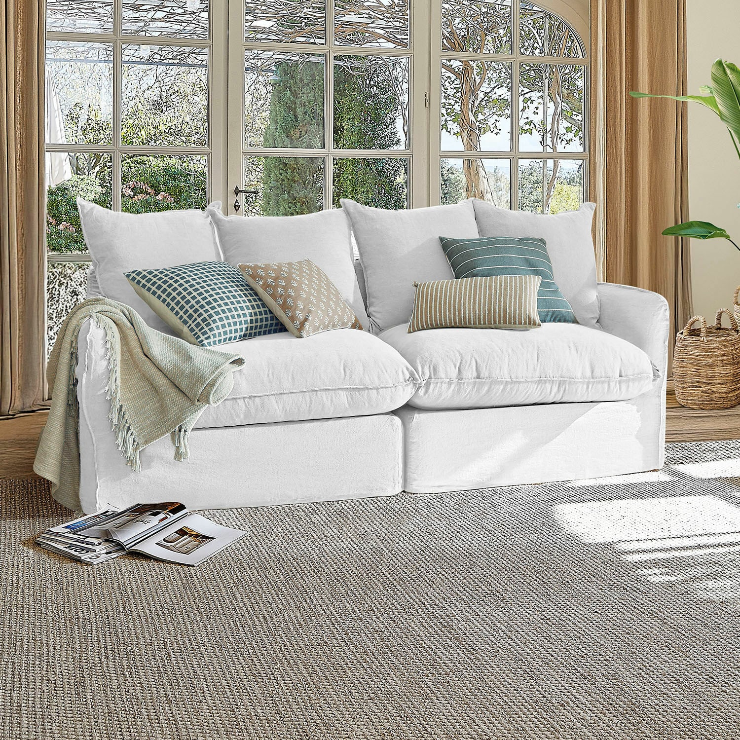 Sofá Dunswater Sofá blanco de tela con cojines de varios diseños en sala luminosa con grandes ventanas