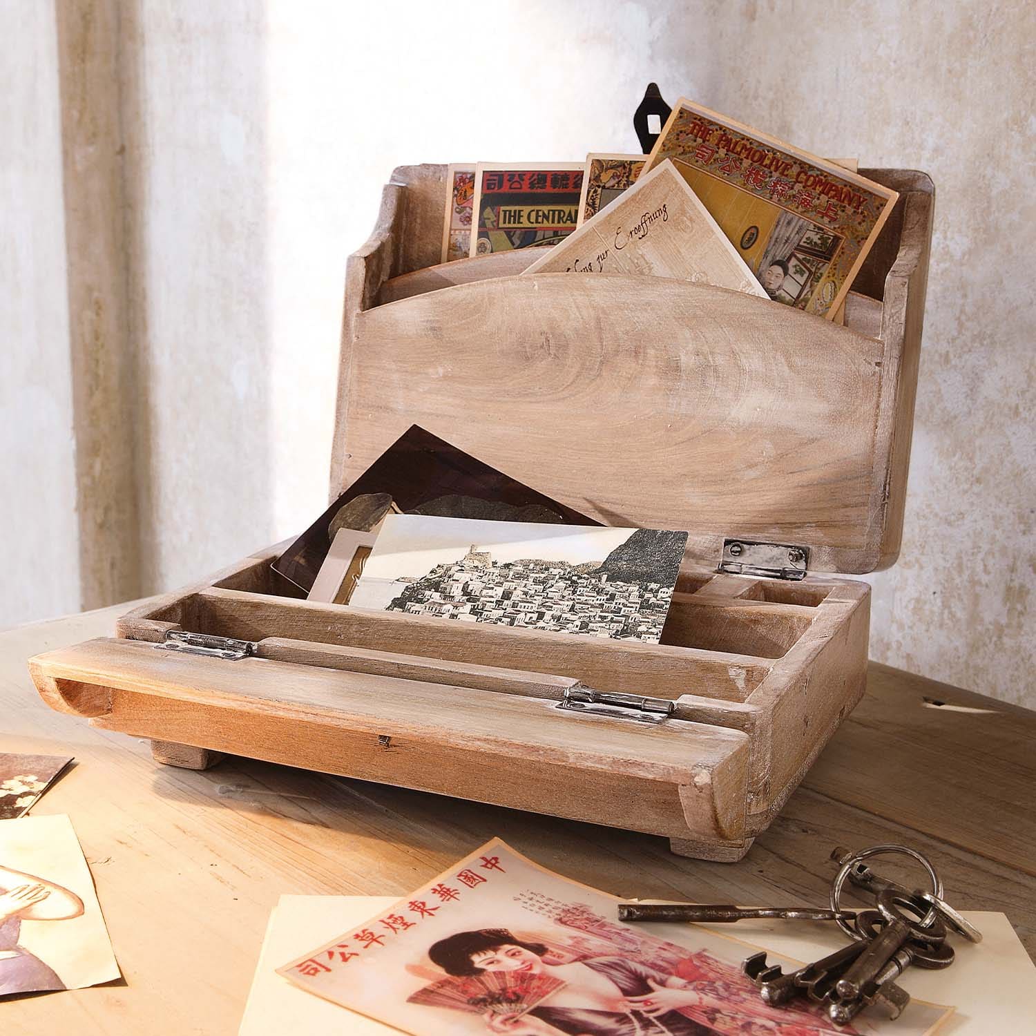Caja de madera natural para cartas con postales vintage y llaves metálicas sobre mesa de madera