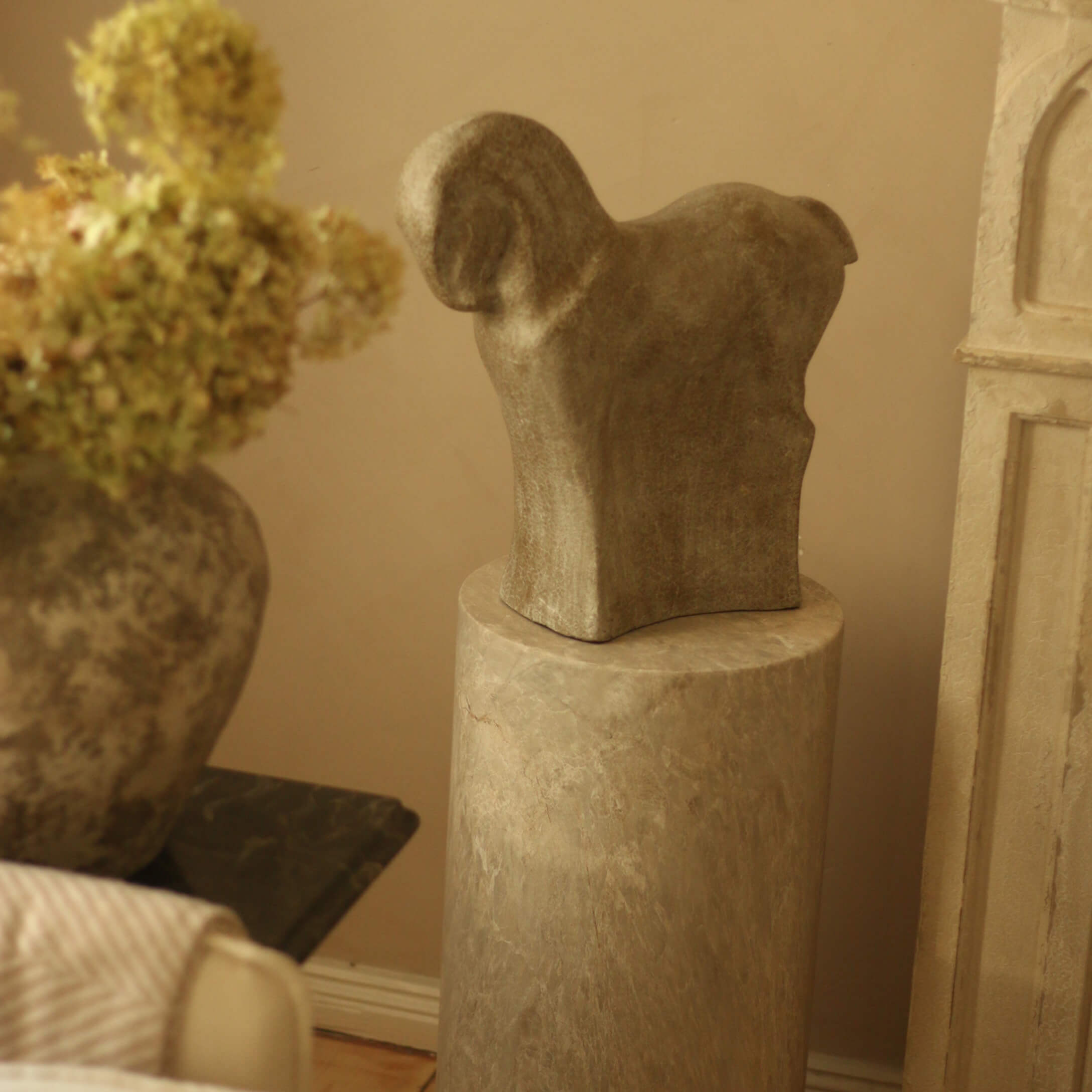 Escultura de piedra con forma de animal sobre pedestal de mármol en interior cálido