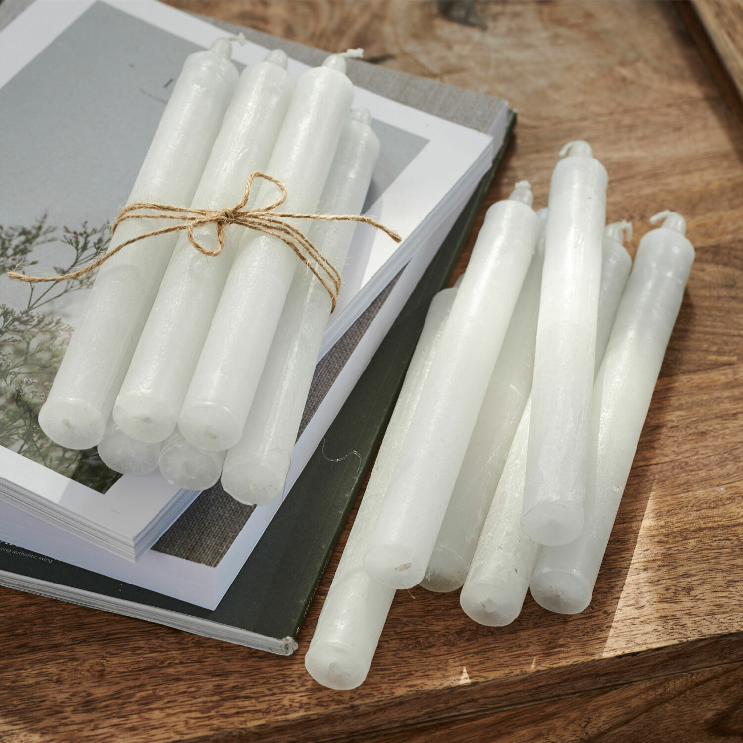 Set de 12 velas Bauceau Conjunto de velas blancas de cera sobre mesa de madera con libros, decoración de interiores