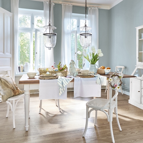 Comedor rústico con mesa y sillas blancas de madera, decoraciones en tonos pastel claros