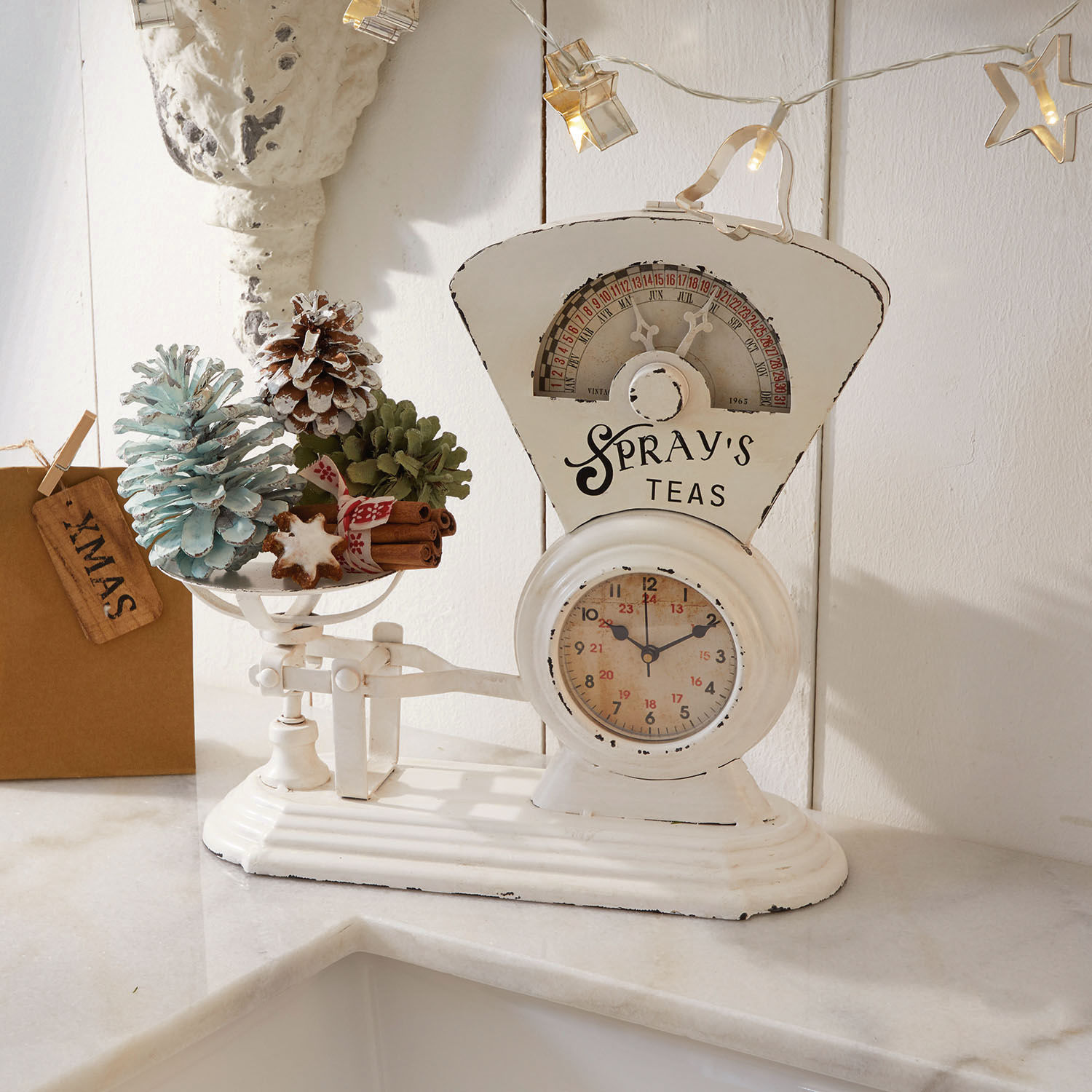 Reloj Balances Báscula de cocina blanca de metal con decoraciones navideñas y piñas sobre encimera