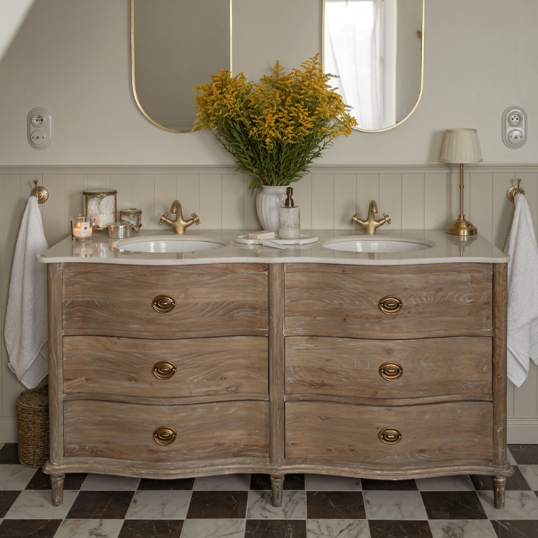 Mueble de baño de madera con encimera de mármol, doble lavabo, grifos dorados y espejos ovalados