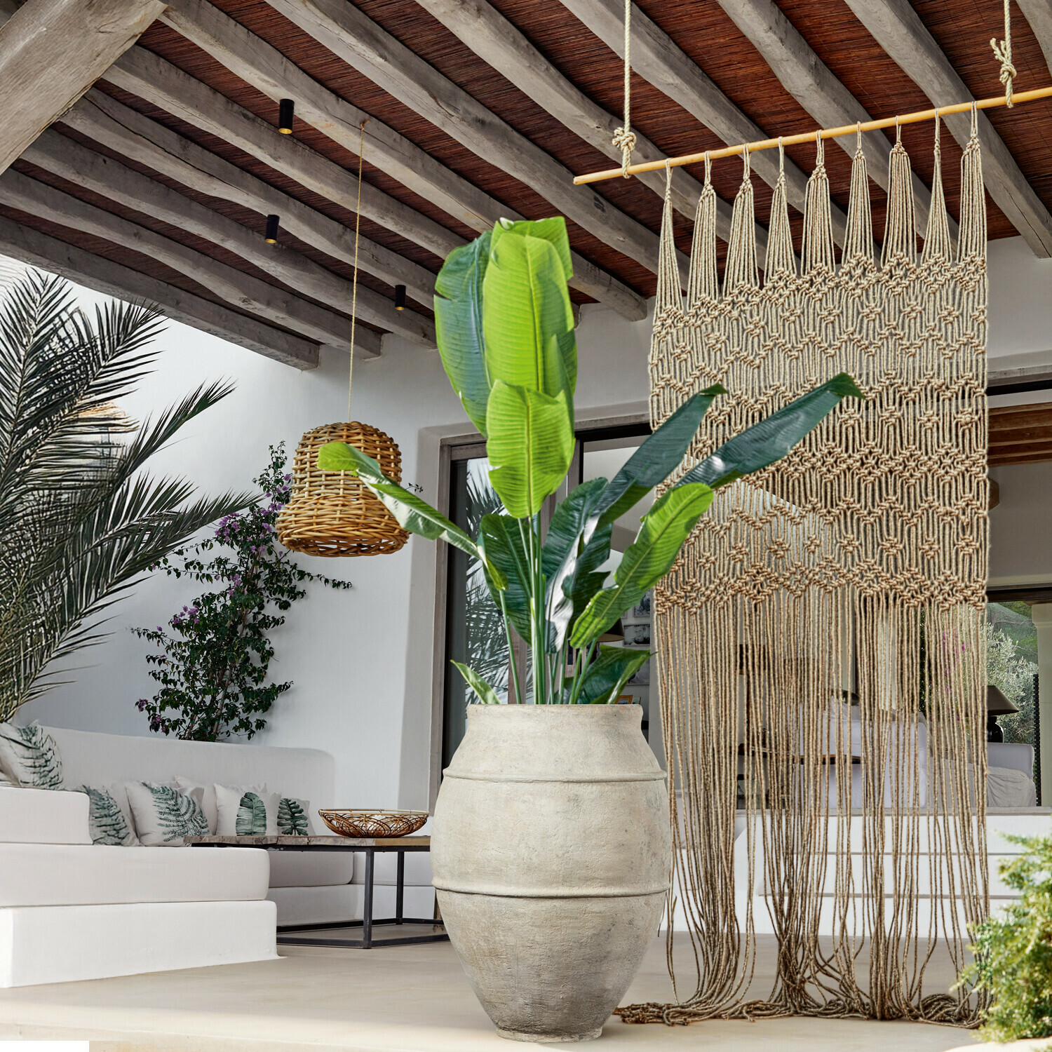 Planta decorativa Lennidas Gran maceta de piedra clara con planta verde en salón moderno con macramé y lámpara de mimbre