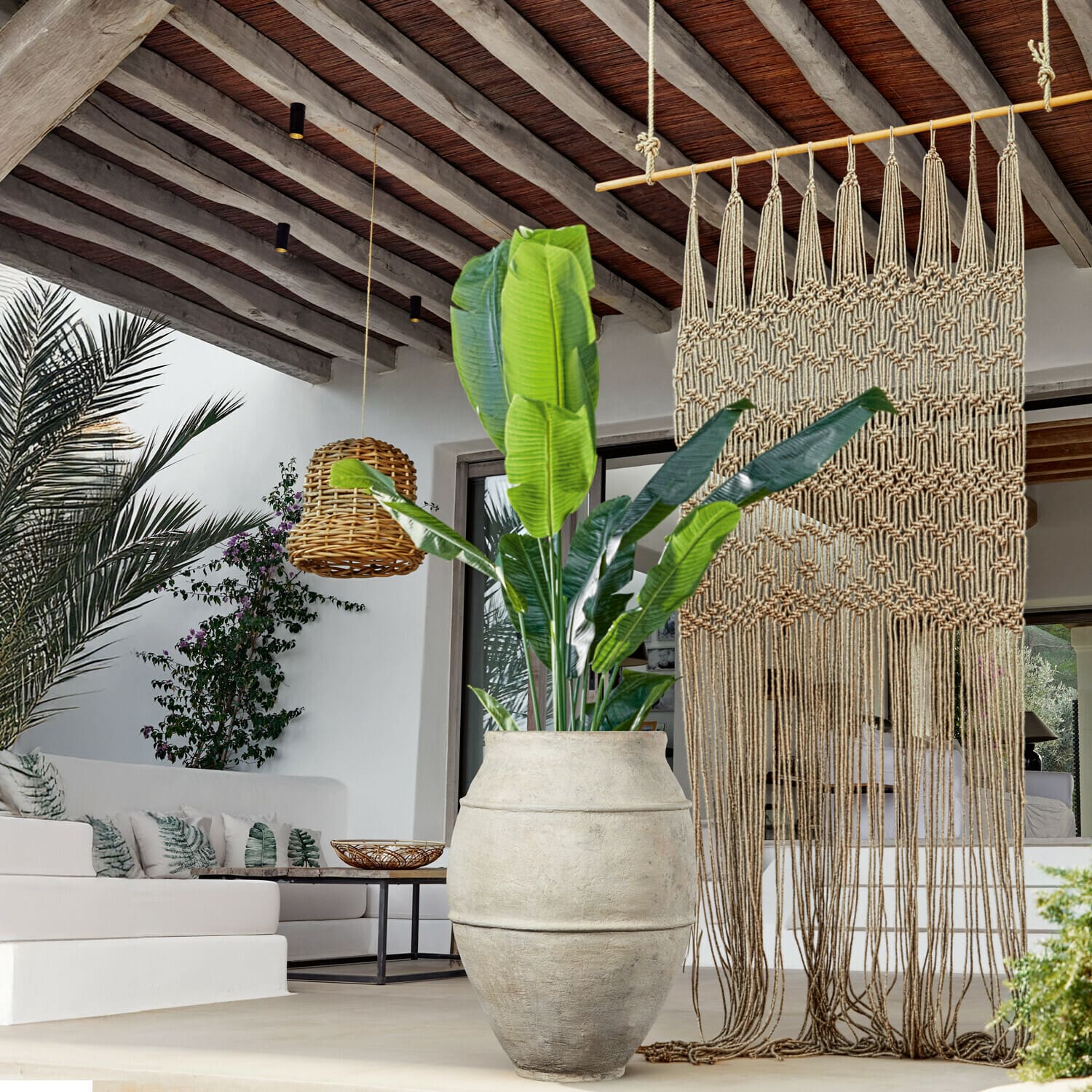 Planta decorativa Lennidas Gran maceta de piedra clara con planta verde en salón moderno con macramé y lámpara de mimbre