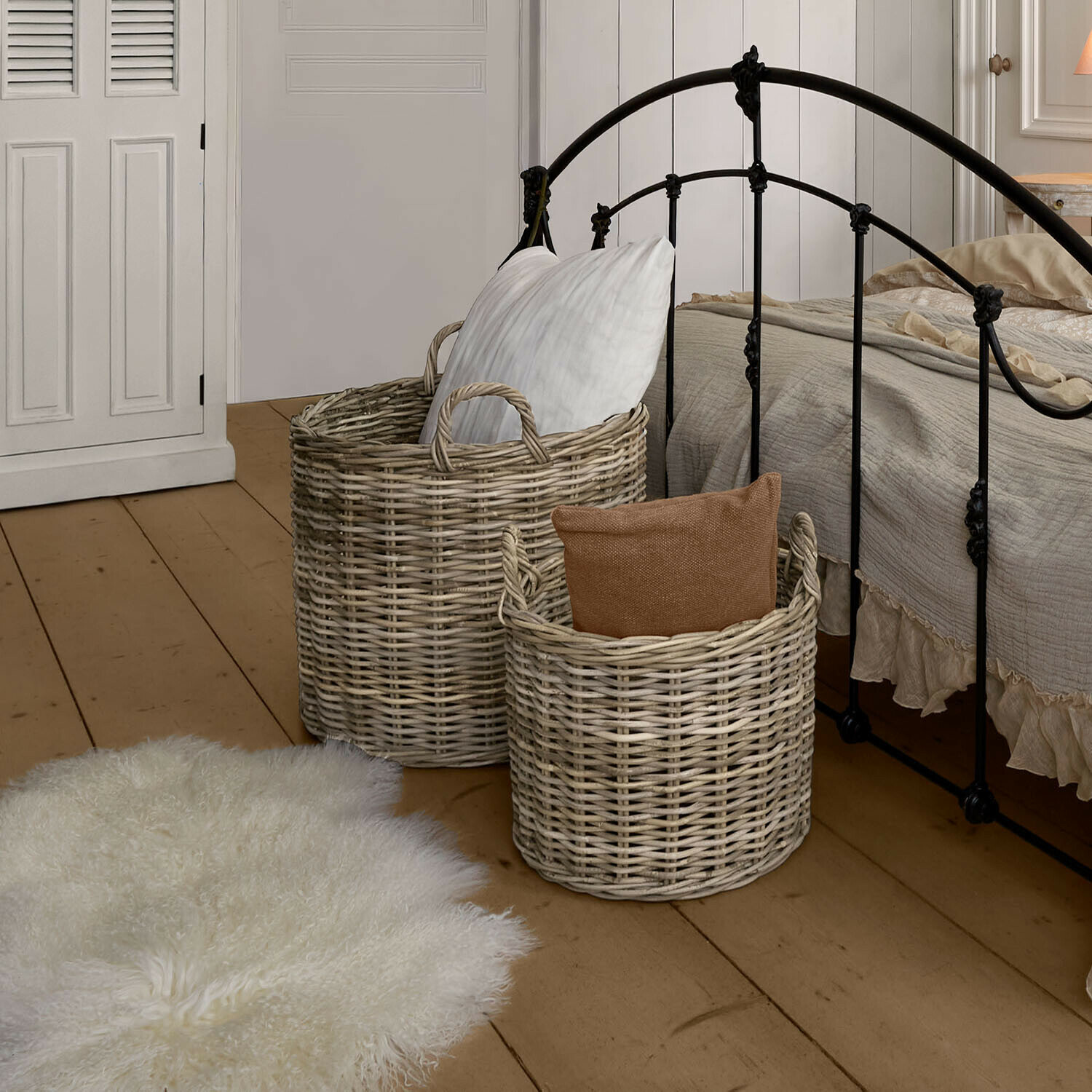 Set de 2 cestas Alouenne Dos cestas de mimbre natural con cojines en dormitorio con cama de metal y suelo de madera