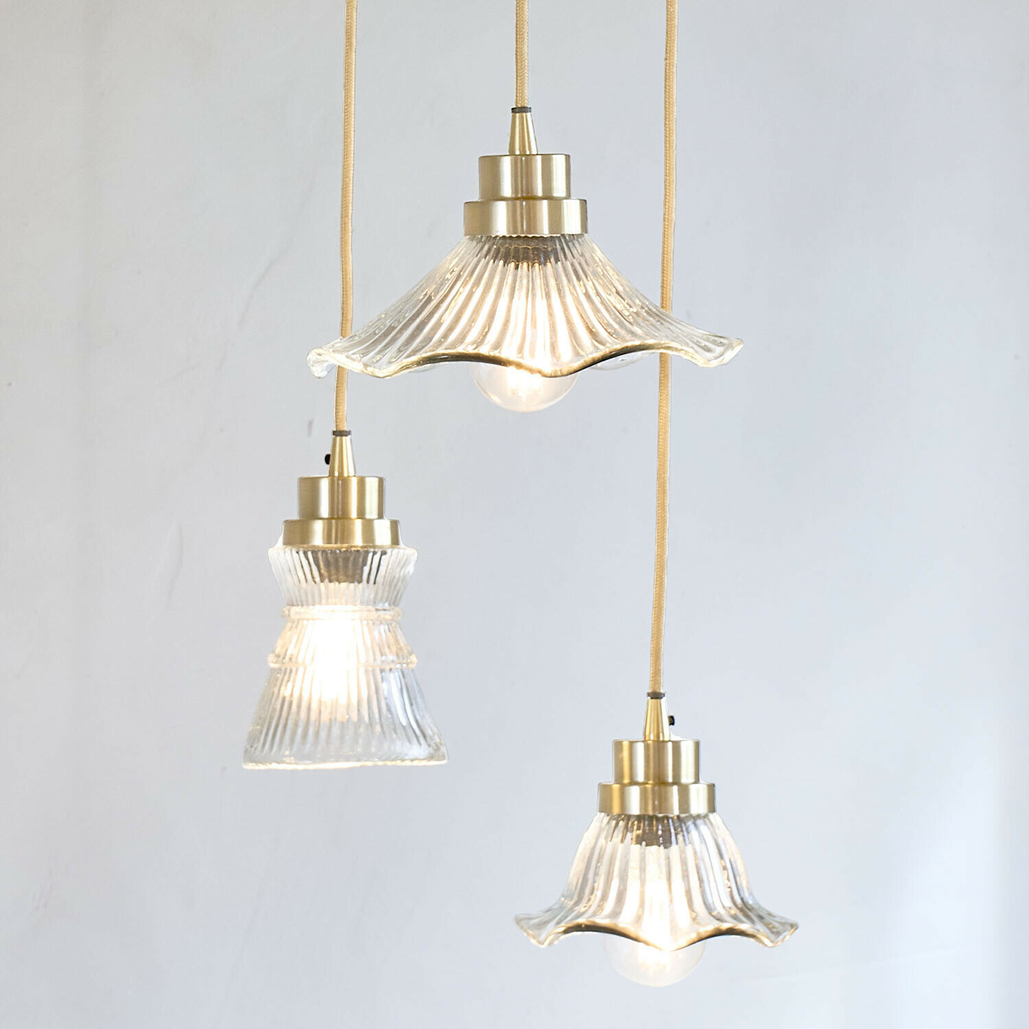 Lámpara colgante Lunaras Conjunto de tres lámparas colgantes de vidrio con detalles de latón y cable amarillo para iluminación interior