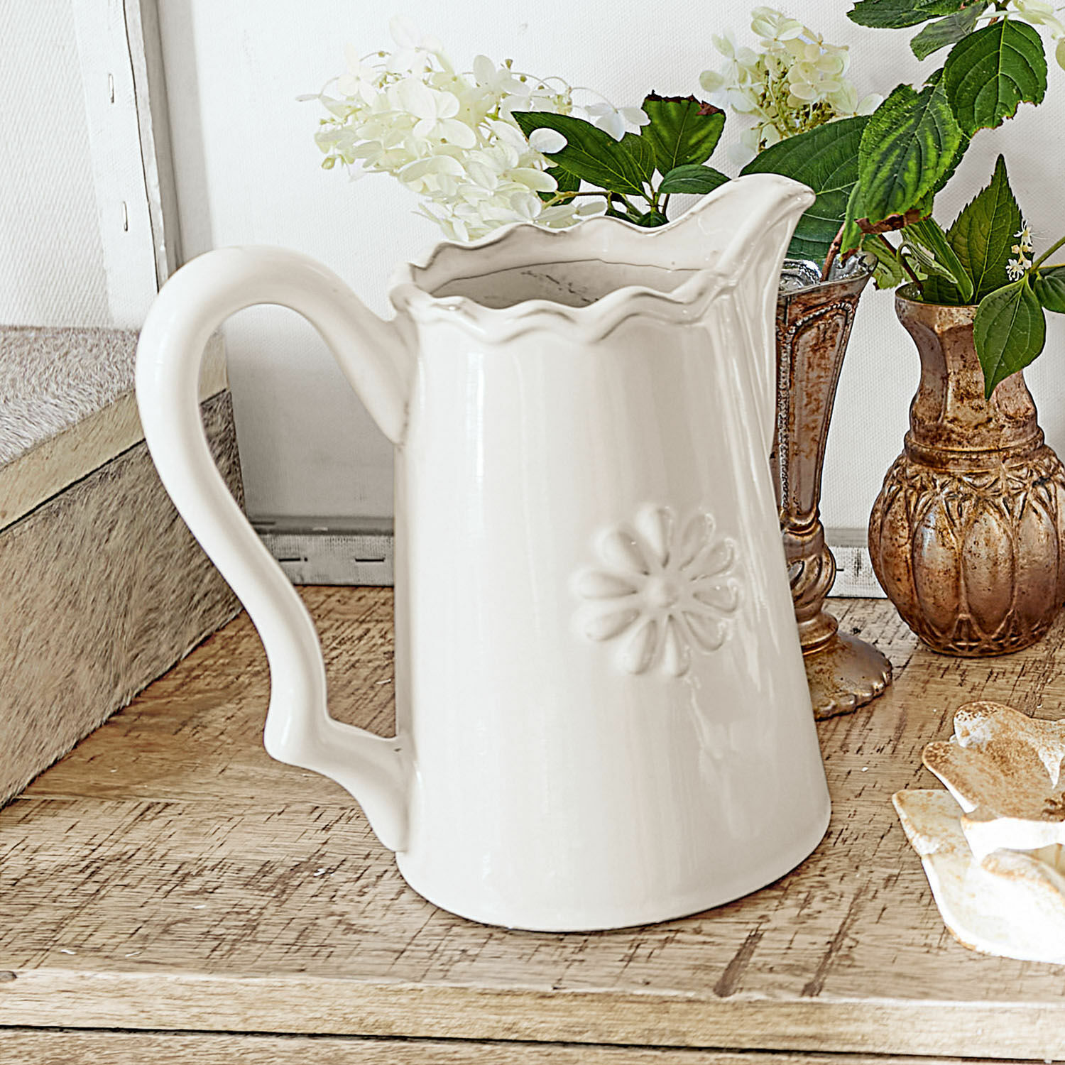 Jarra Mallevesse Jarra de cerámica blanca con diseño floral en relieve sobre mesa de madera, decoración interior