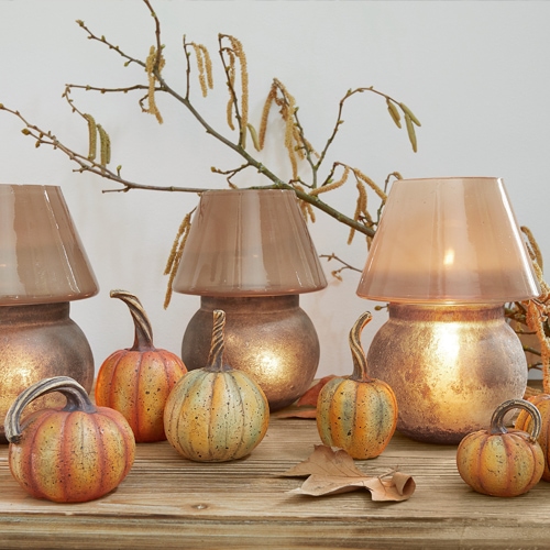 Faroles decorativos de vidrio y metal cobre con adornos de calabaza sobre mesa de madera