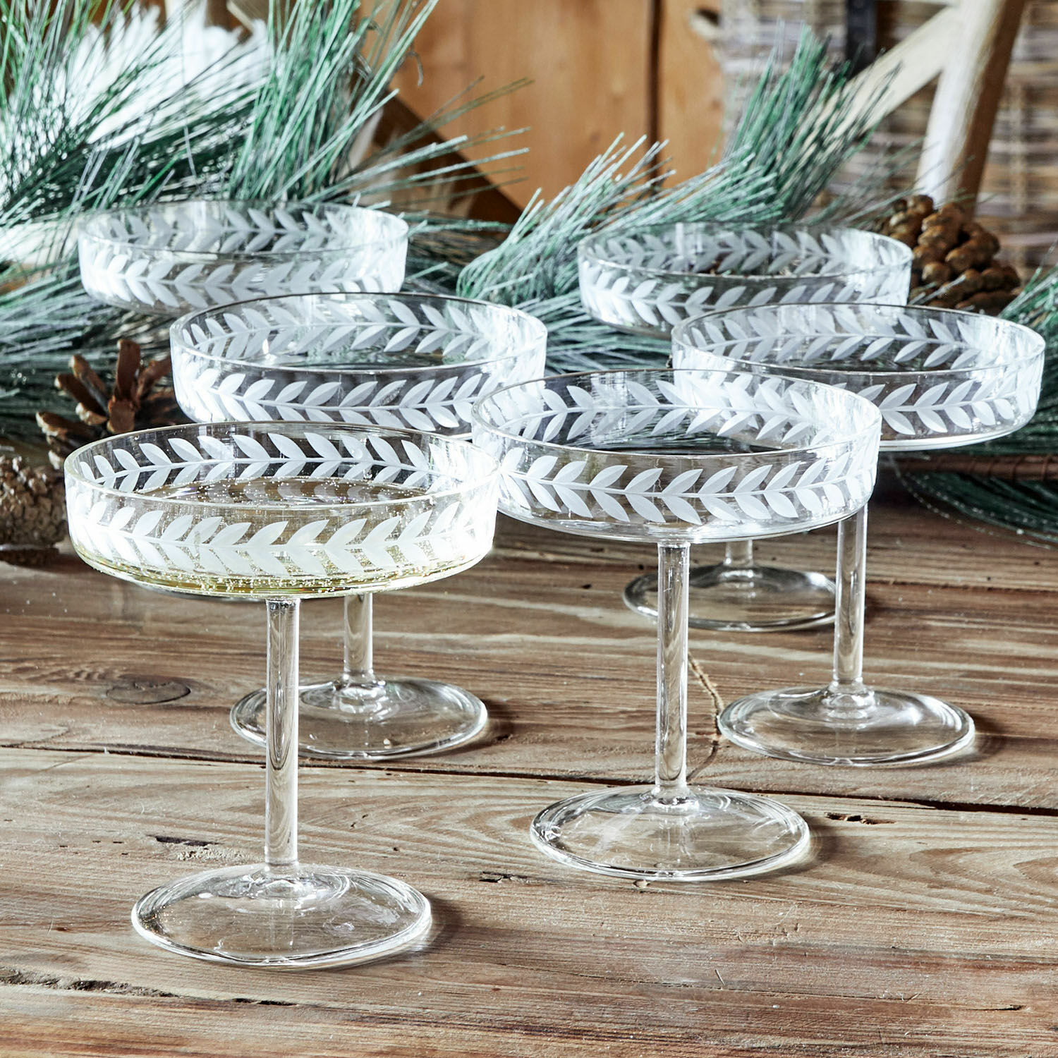 Set de 6 copas de champán Macomb Conjunto de seis copas de champán de vidrio con diseño grabado de hojas sobre mesa de madera