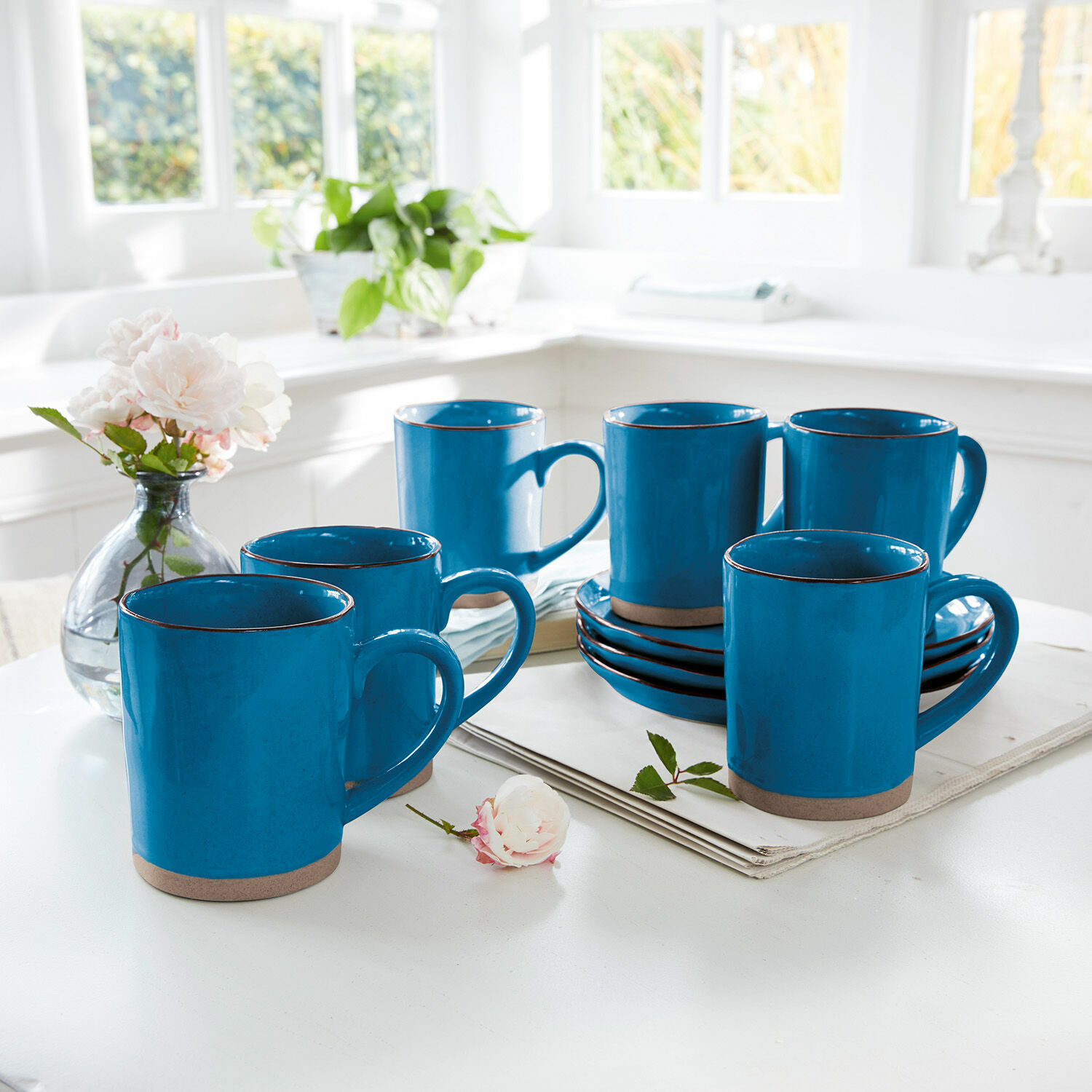 Set de 6 tazas Biarré Juego de seis tazas de cerámica azul con base marrón sobre mesa blanca en cocina luminosa