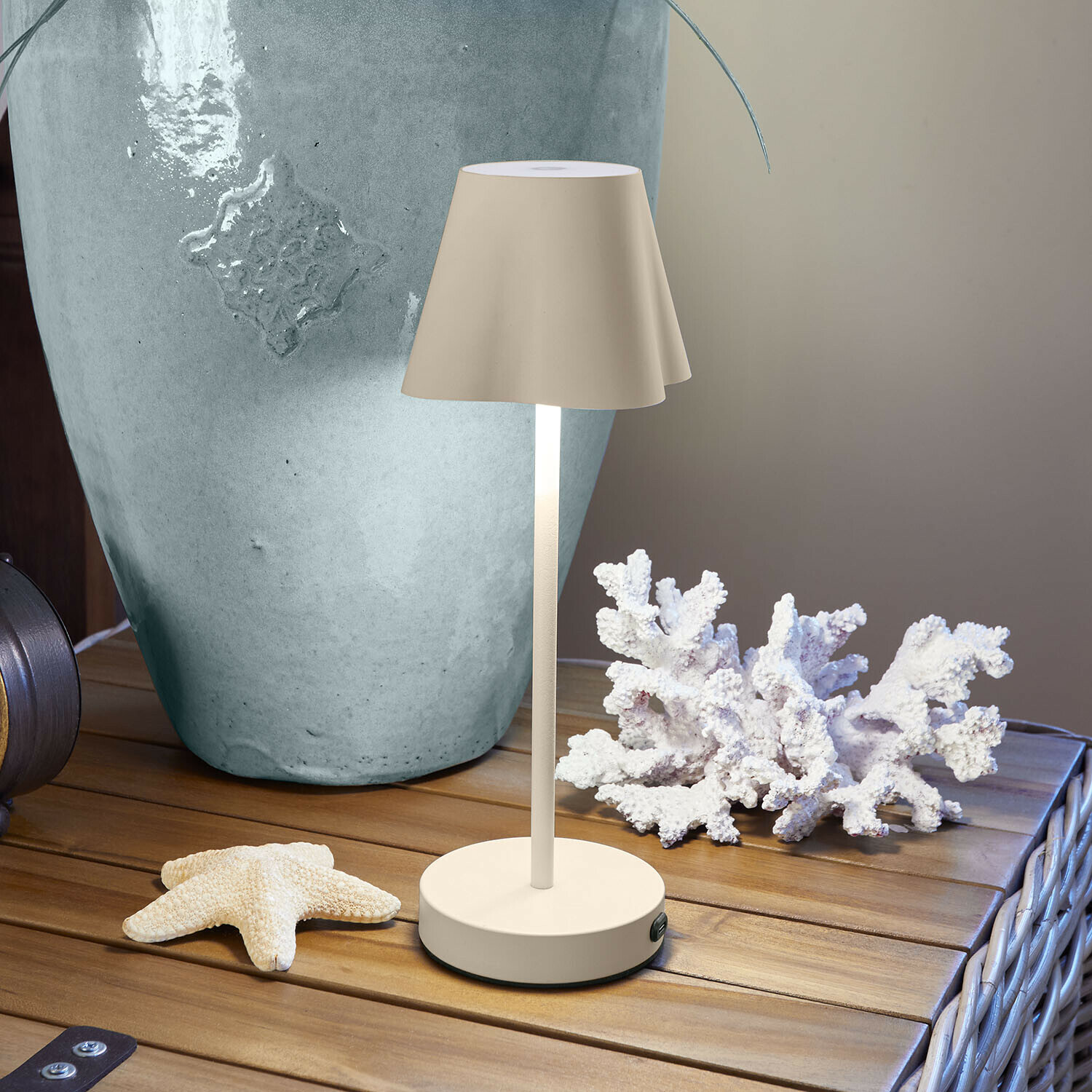 Lámpara de mesa recargable Tenari Lámpara de mesa beige de metal sobre mesa de madera con decoración marina y jarrón grande