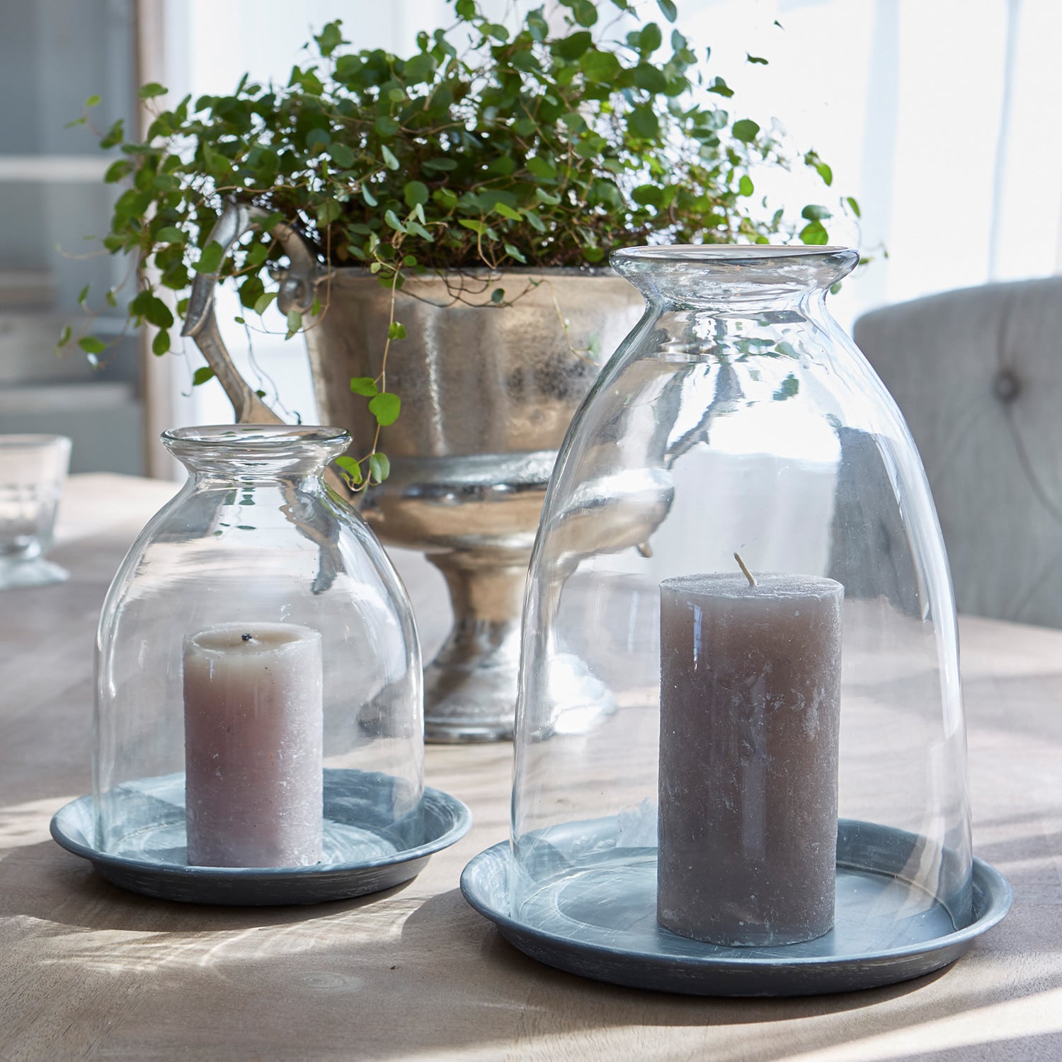 Set de 2 farolillos Gwendale Velas grises bajo campanas de vidrio transparentes sobre bases metálicas grises en una mesa