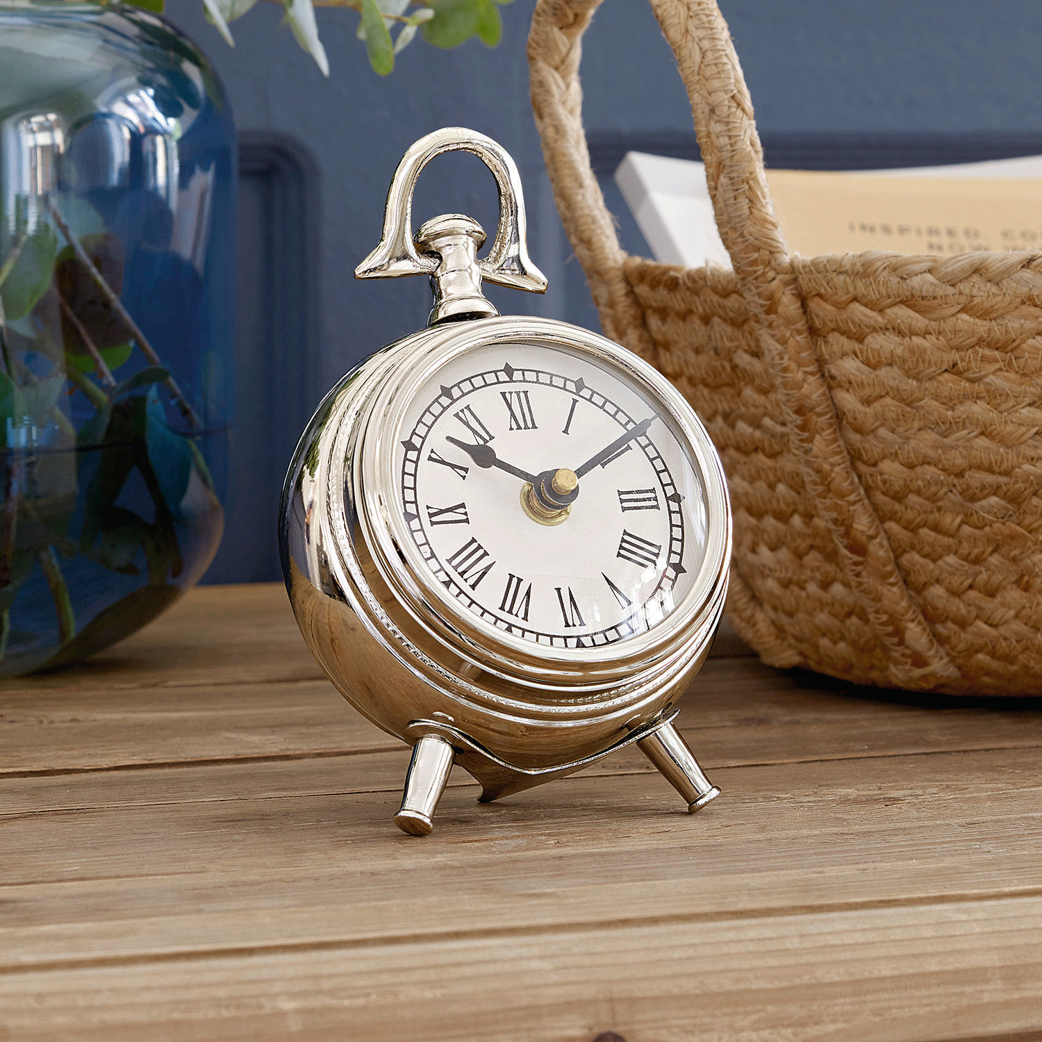 Reloj Coraten Reloj de mesa metálico plateado con números romanos sobre superficie de madera, decoración interior
