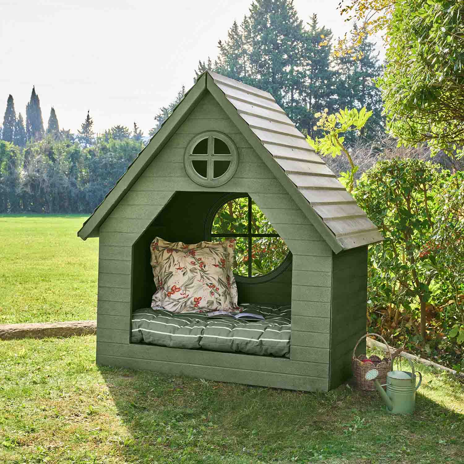 Caseta de jardín verde de madera con cojín y ventana redonda, perfecta para relajarse al aire libre