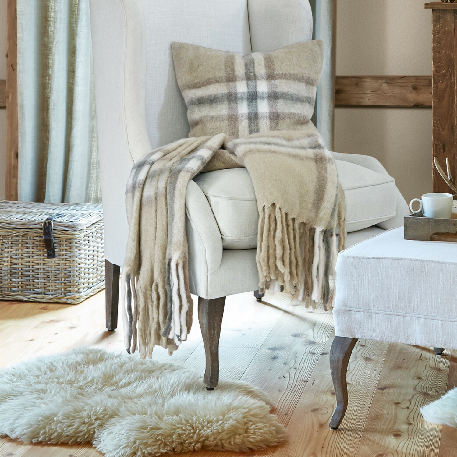 Plaid Klinas Sillón y reposapiés beige de tela en sala acogedora con suelo de madera y chimenea