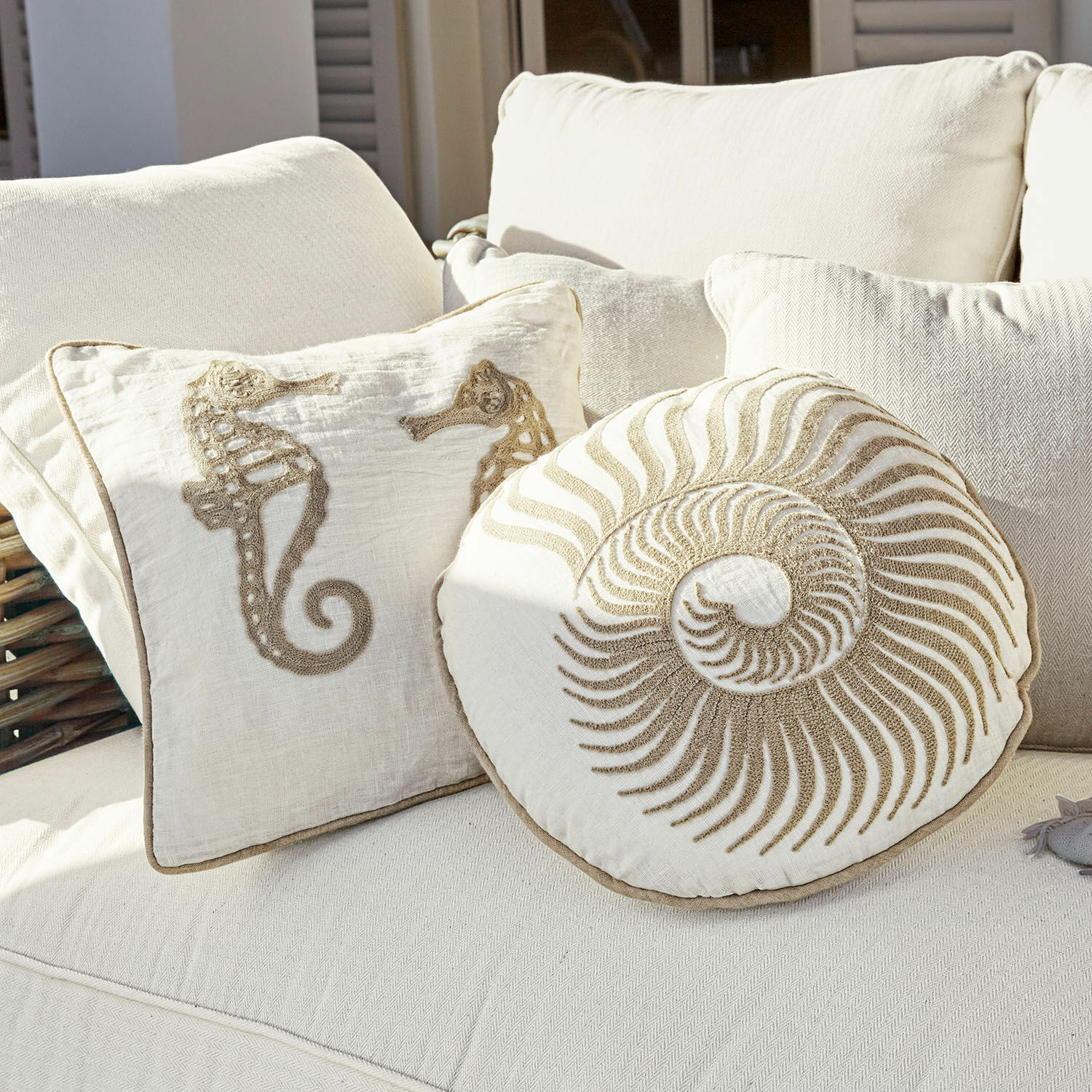 Set de 2 cojines Bristol Cojines decorativos de algodón crema con motivos de caballitos de mar y concha en sofá claro