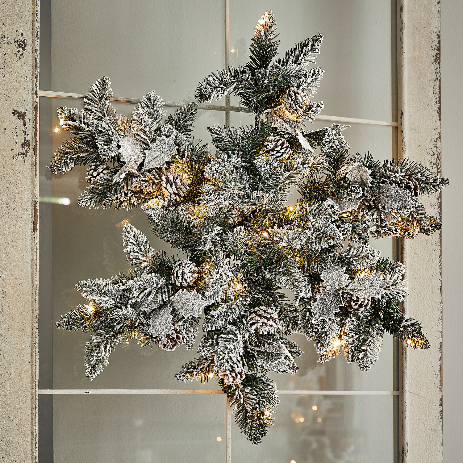 Copo de nieve LED Azimara Adorno navideño en forma de estrella con ramas verdes, piñas con efecto nieve y luces LED cálidas