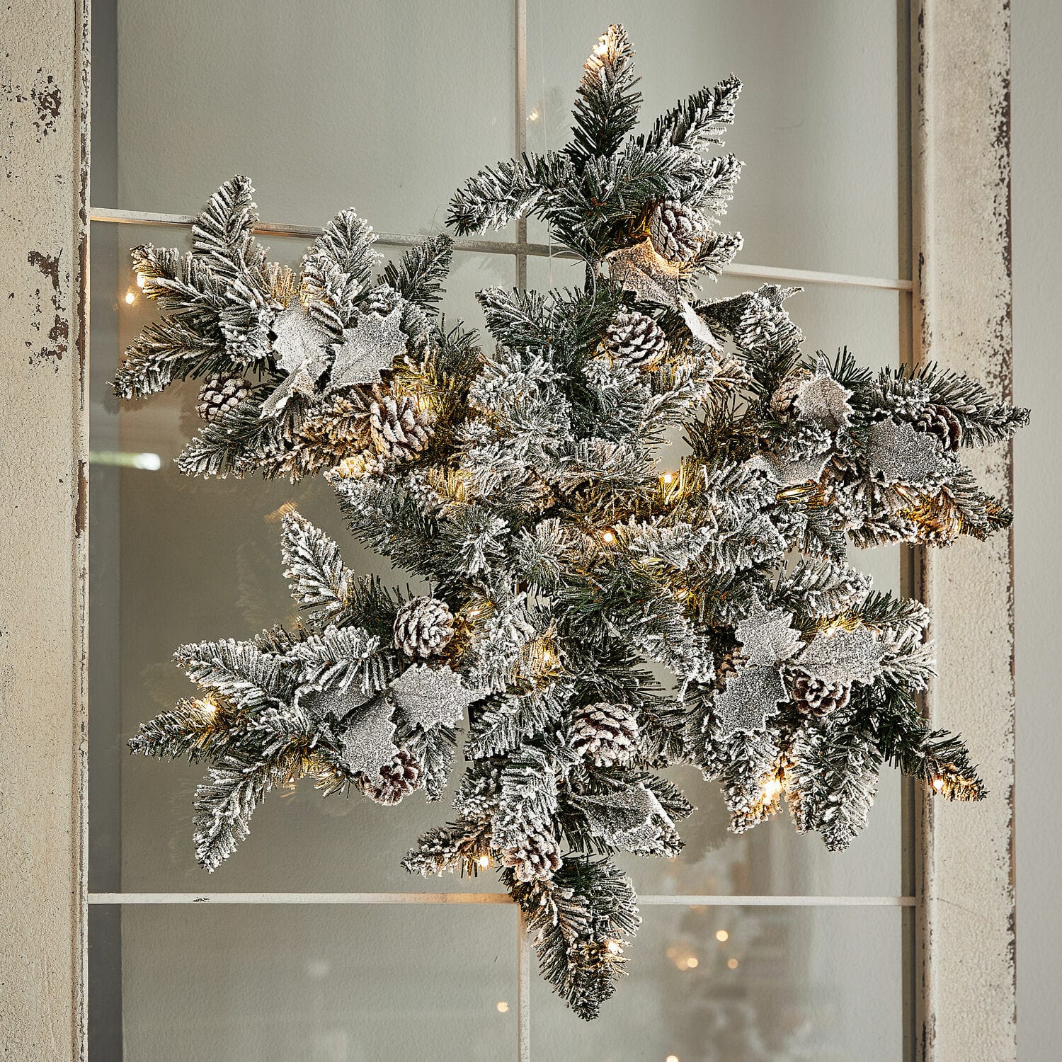 Copo de nieve LED Azimara Adorno navideño en forma de estrella con ramas verdes, piñas con efecto nieve y luces LED cálidas