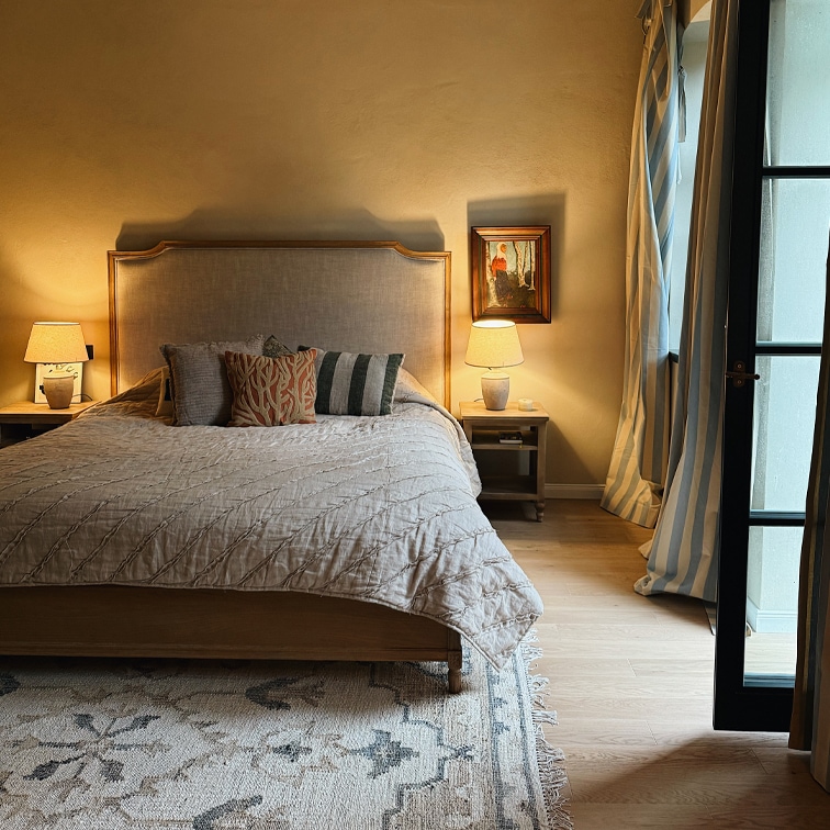 Dormitorio acogedor con cama de madera, edredón beige y lámparas en mesitas de noche de madera