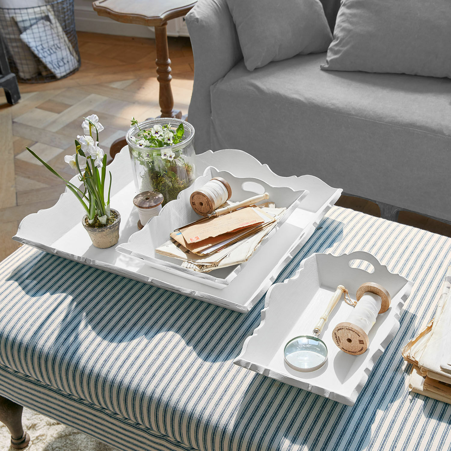 Set de 3 bandejas Pirelo Bandejas decorativas de madera blanca sobre tapizado a rayas con plantas y accesorios de escritura