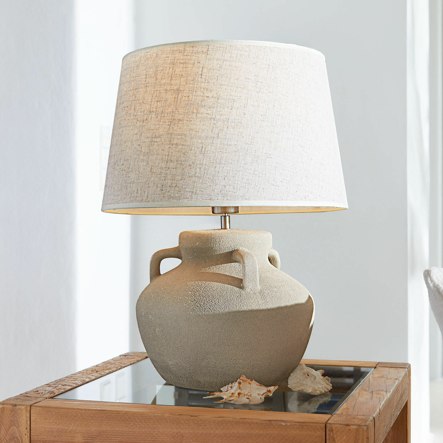Lámpara de mesa Parya Lámpara de mesa con base de cerámica beige y pantalla clara sobre mesa de madera