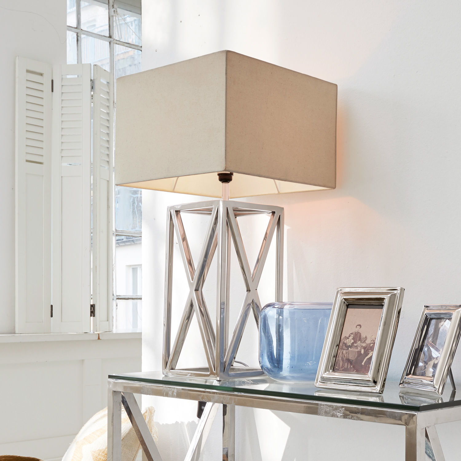 Lámpara de mesa Foix Lámpara de mesa moderna con base metálica y pantalla beige sobre mesa de cristal en interior luminoso