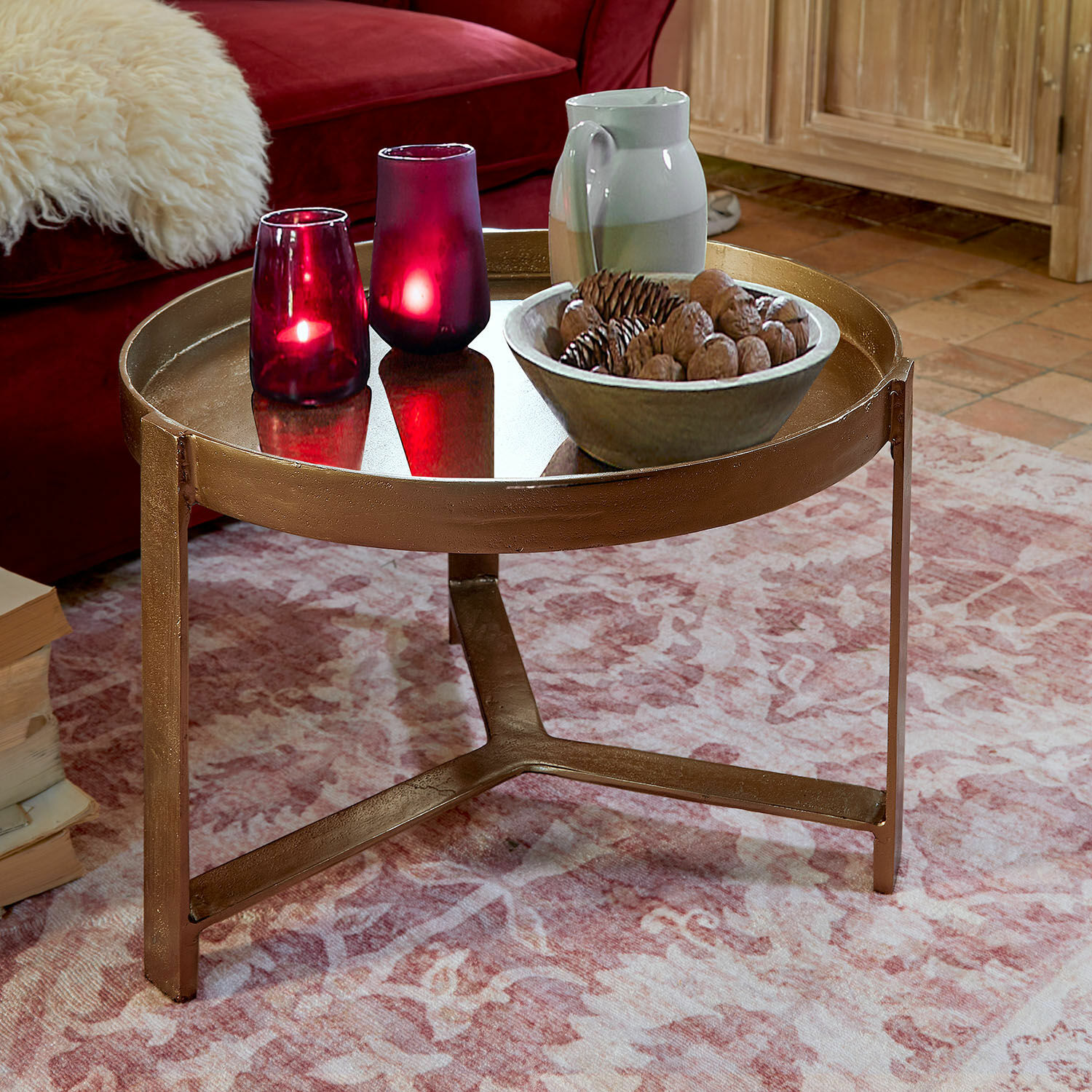 Mesa de centro Mirouette Mesa de centro redonda de metal color cobre sobre alfombra rosa con velas decorativas y cuenco