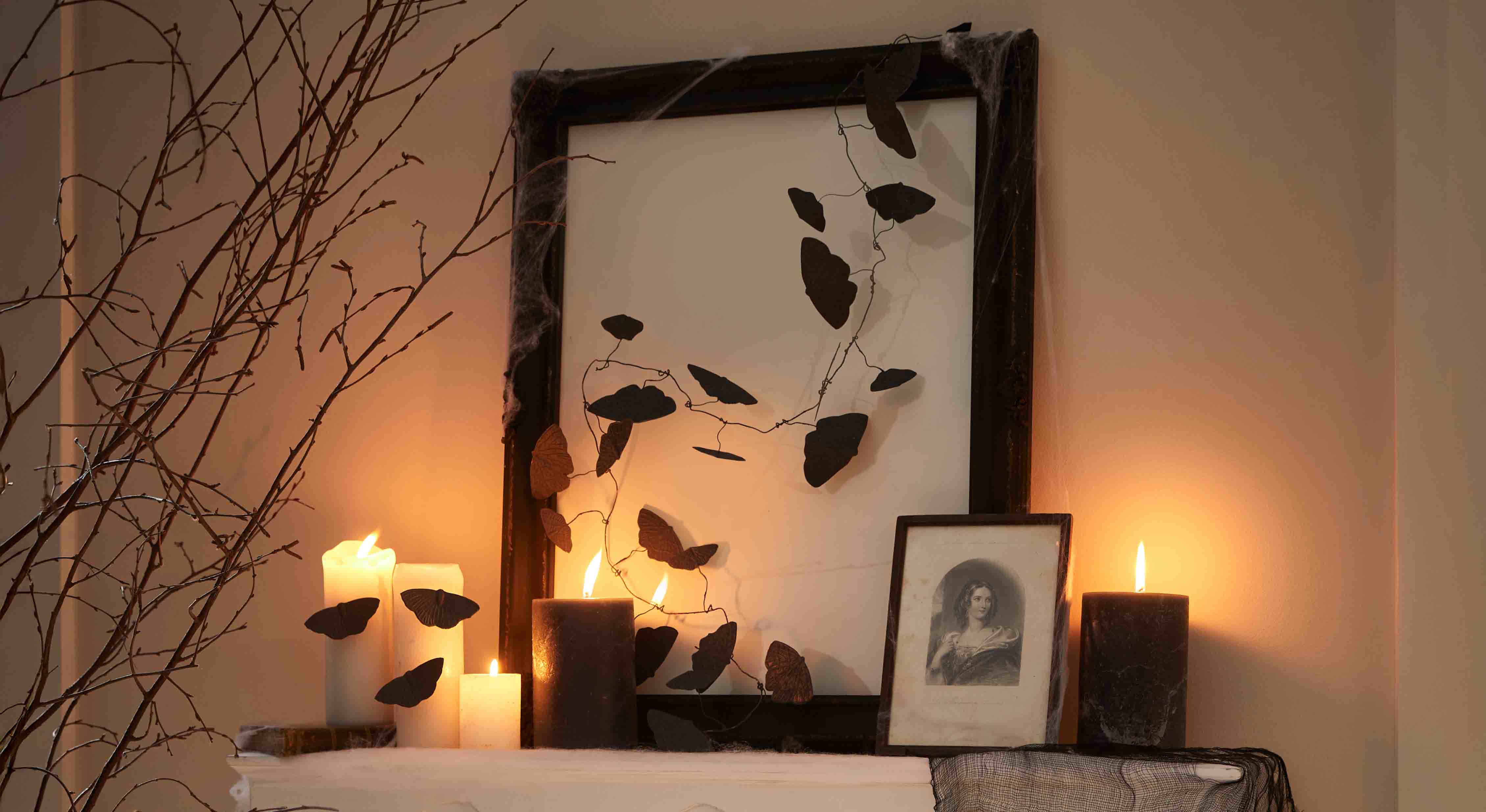 Velas negras y blancas con decoración de mariposas de alambre en marco, iluminación ambiental cálida