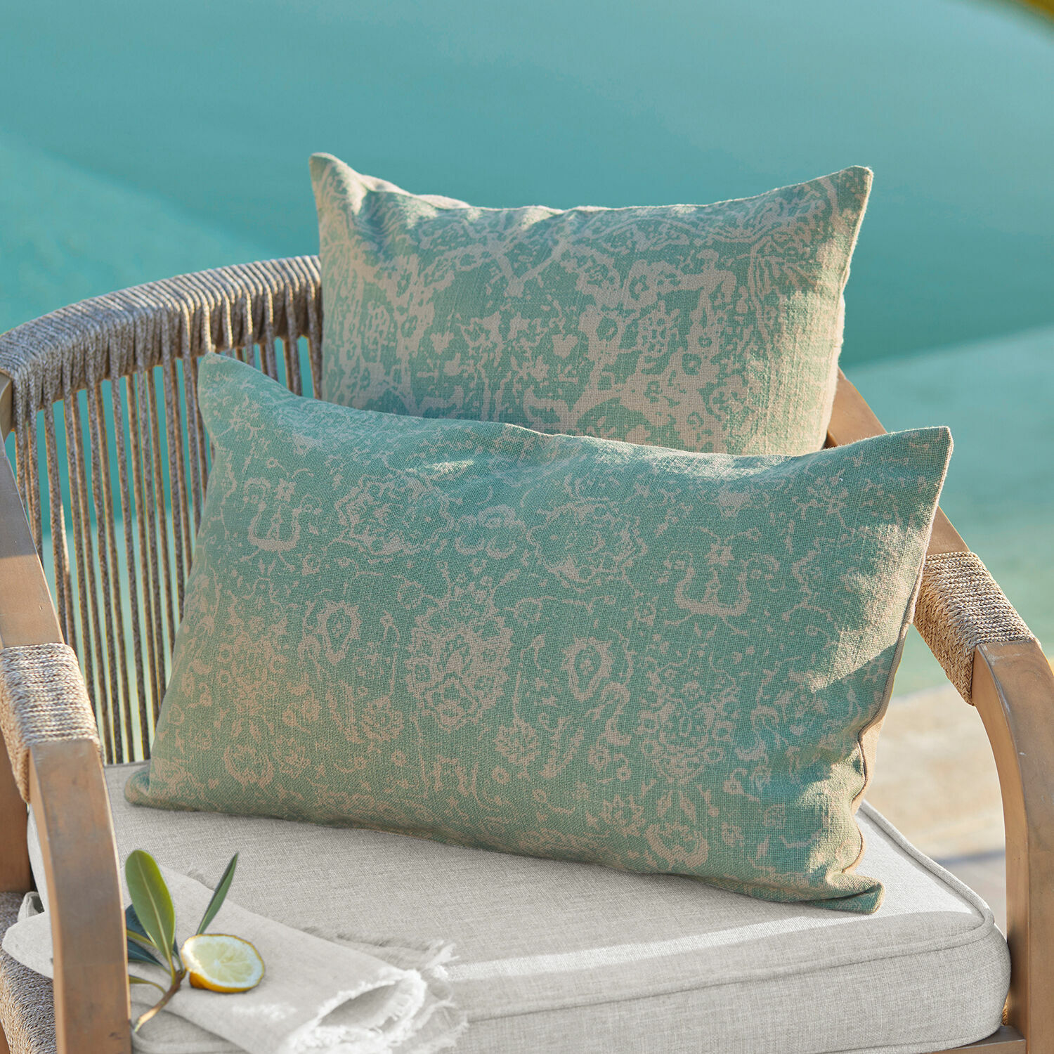 Set de 2 fundas de cojín Morwell Cojines decorativos de algodón bicolor verde y beige con patrón sobre silla de jardín