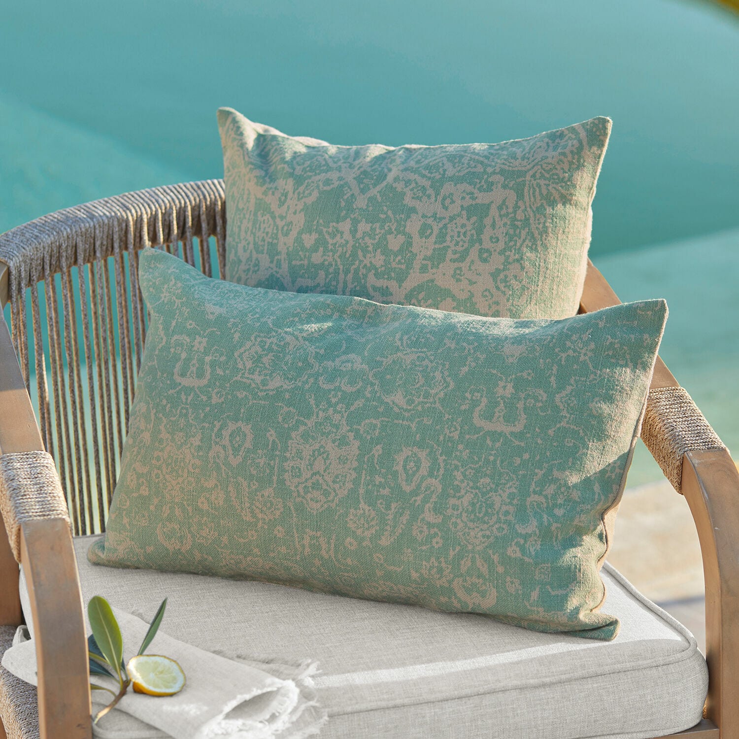 Set de 2 fundas de cojín Morwell Cojines decorativos de algodón bicolor verde y beige con patrón sobre silla de jardín