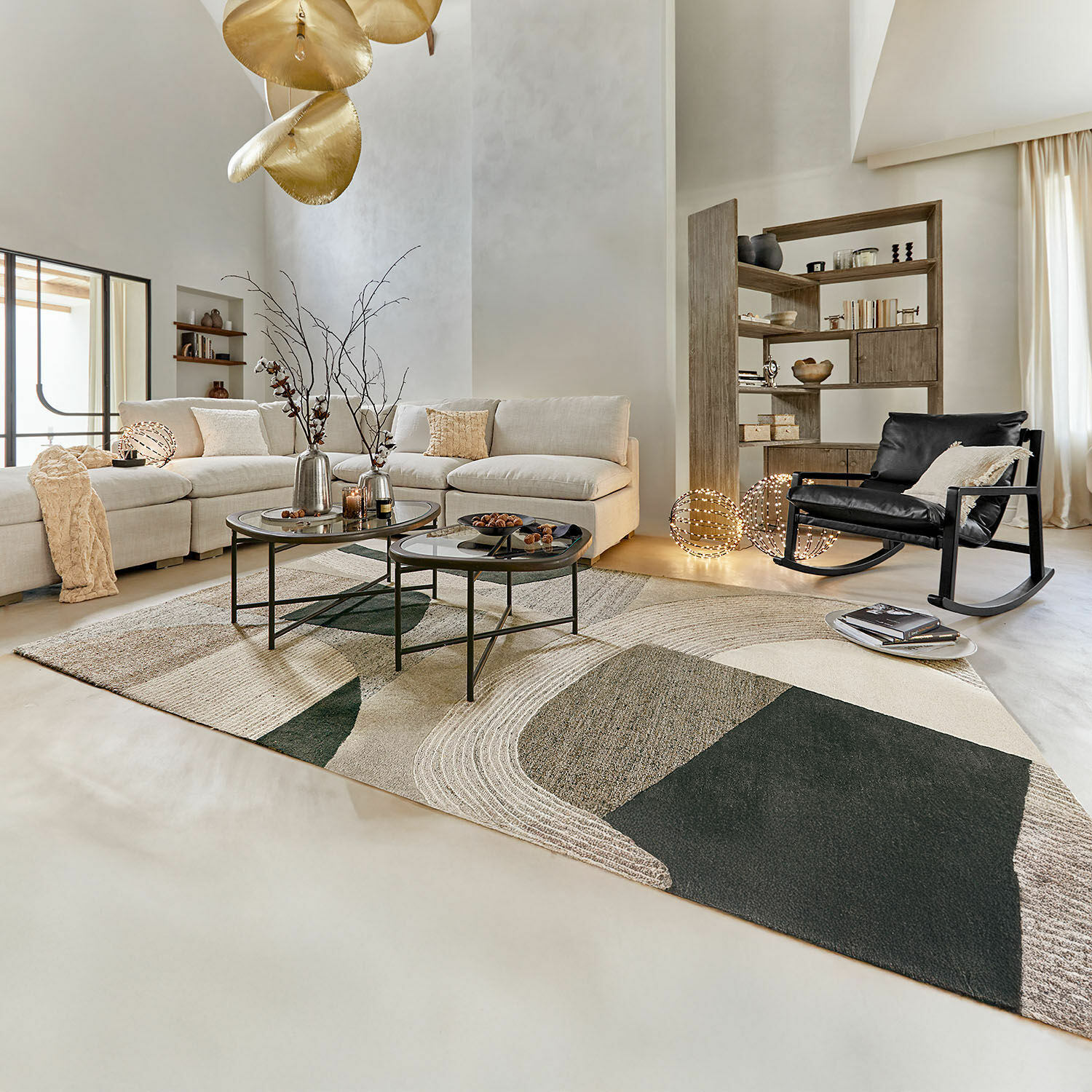 Salón moderno con sofá beige, mecedora negra y alfombra geométrica en tonos naturales