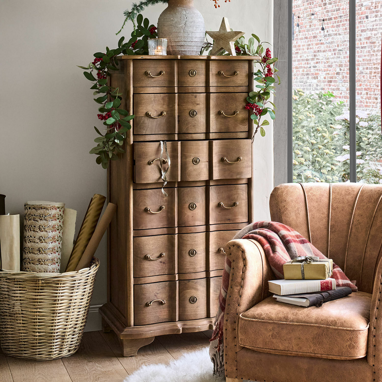 Cómoda Aiguillon Cómoda de madera con tiradores decorativos y guirnalda de hojas verdes con bayas rojas en interior acogedor