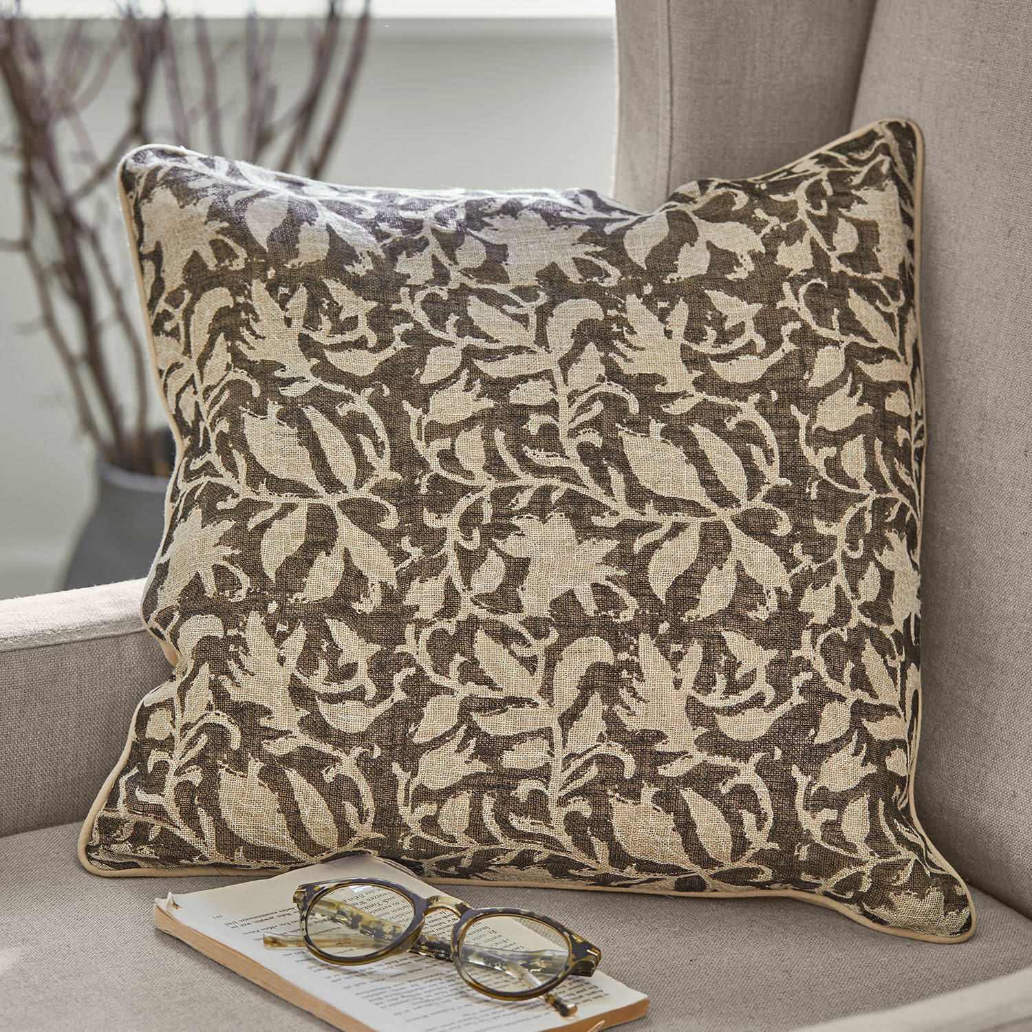 Set de 2 fundas de cojín Ziradayn Cojín decorativo de algodón marrón y beige con diseño vegetal sobre sofá gris con gafas y libro