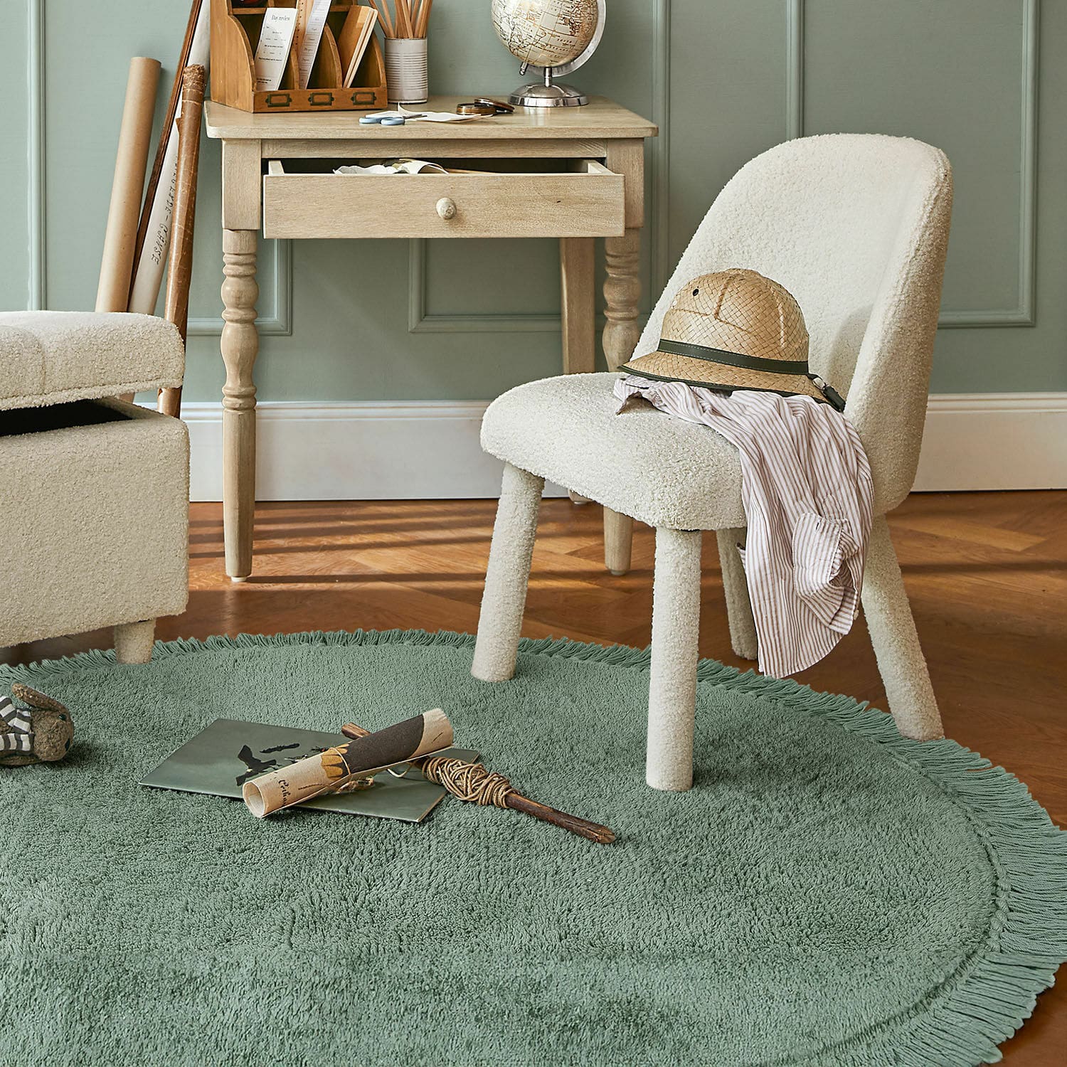 Alfombra Ivalex Silla tapizada crema sobre alfombra redonda verde con flecos en habitación con escritorio de madera clara