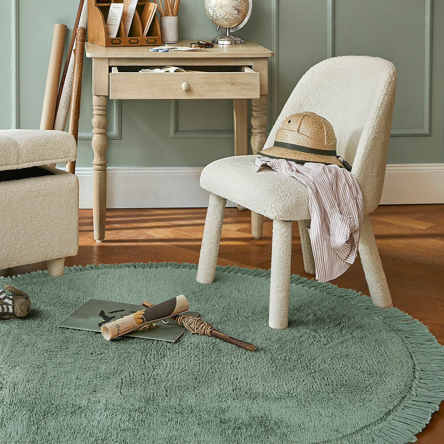 Alfombra Ivalex Silla tapizada crema sobre alfombra redonda verde con flecos en habitación con escritorio de madera clara