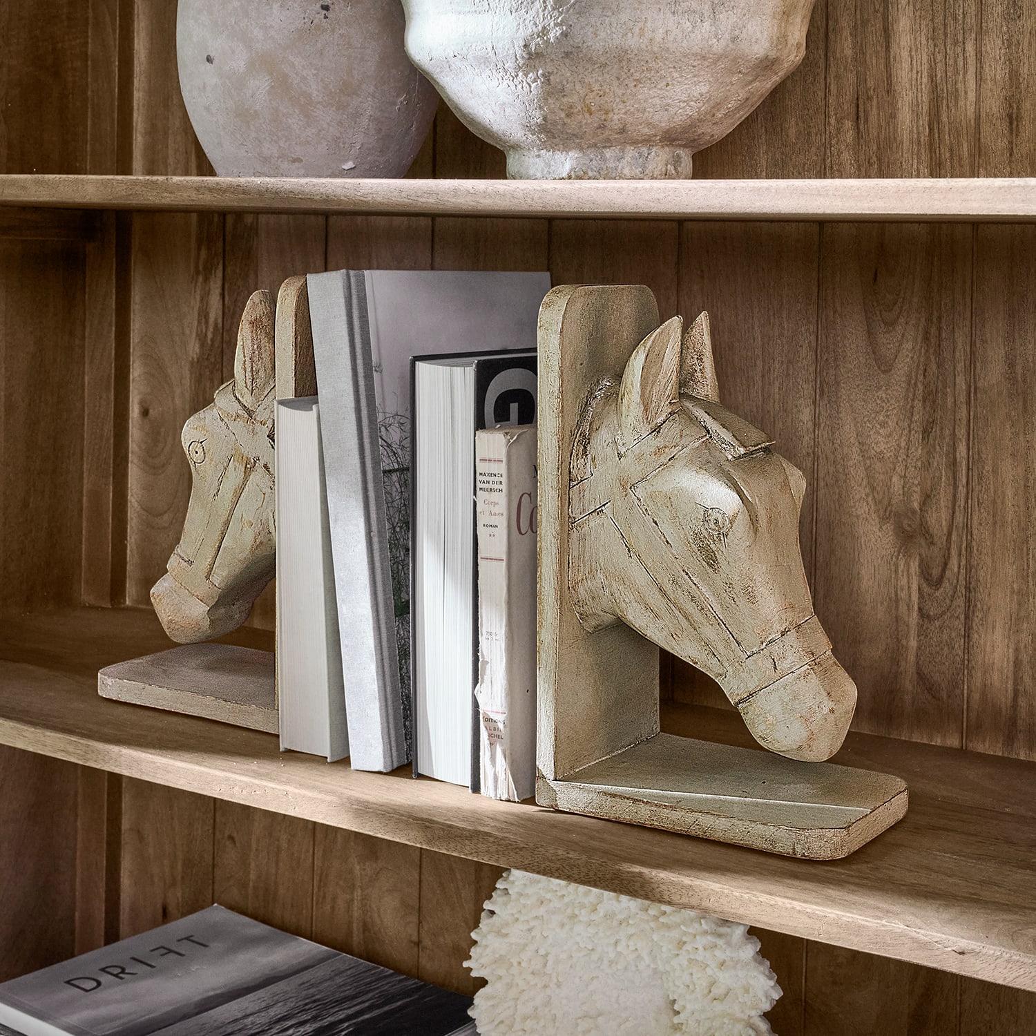 Par de sujetalibros de madera beige con diseño de cabeza de caballo en estantería de madera