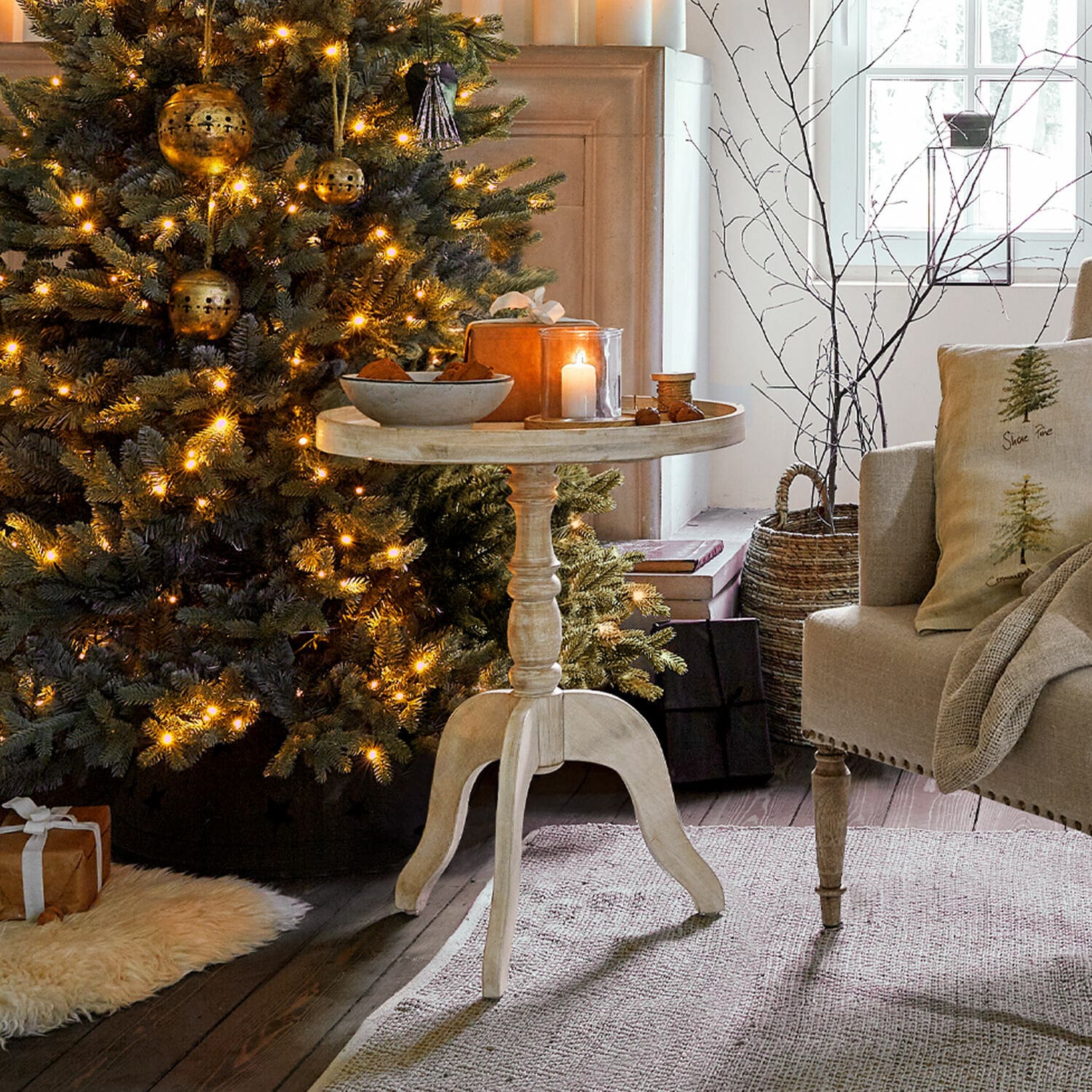 Mesa auxiliar Brookdale Mesa redonda de madera clara junto a un árbol de Navidad iluminado en una sala acogedora