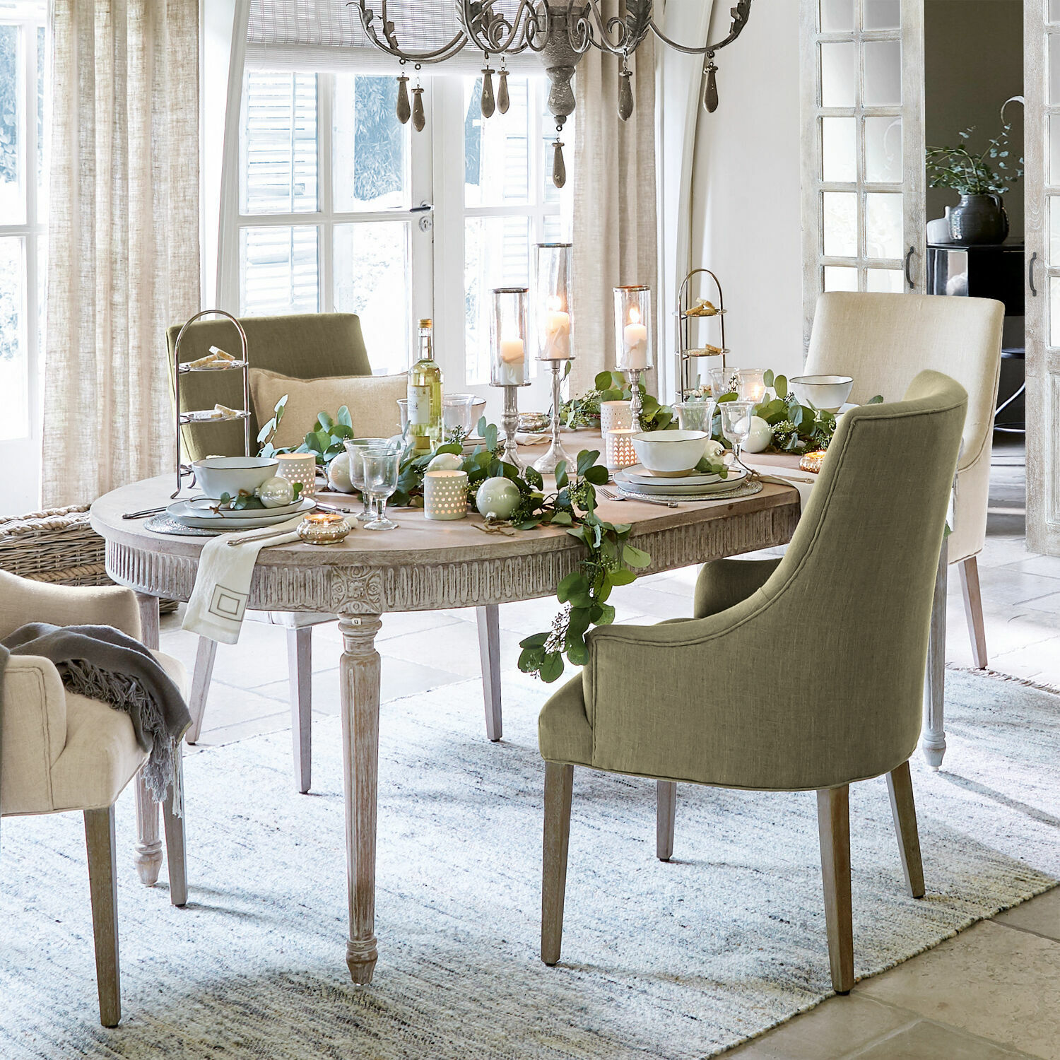Mesa Cienegas Comedor con mesa ovalada de madera y sillas tapizadas verdes y beige, decoración festiva